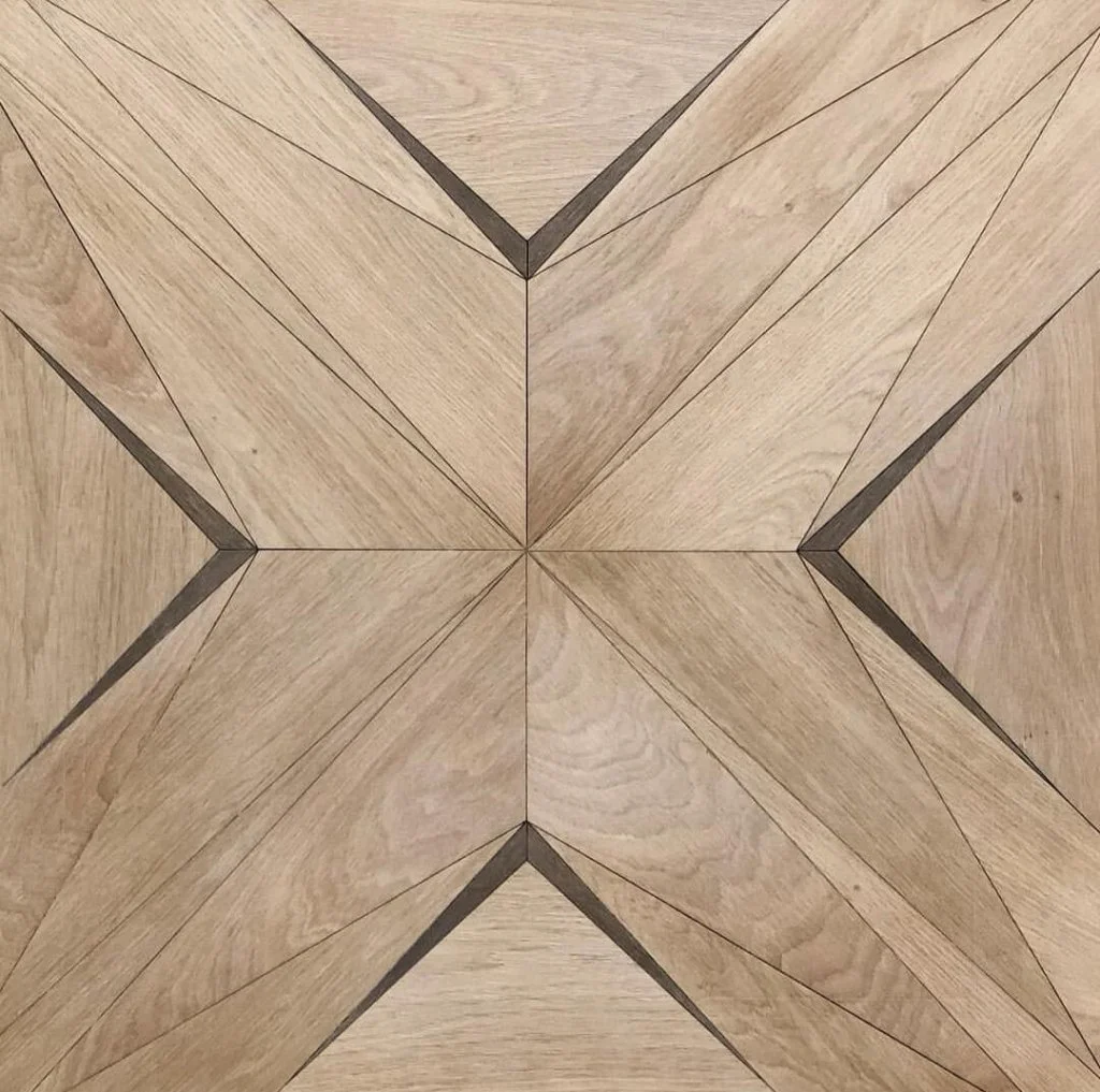 Superficie de madera con un diseño de estrella en el centro formado por varias piezas de madera con líneas rectas.