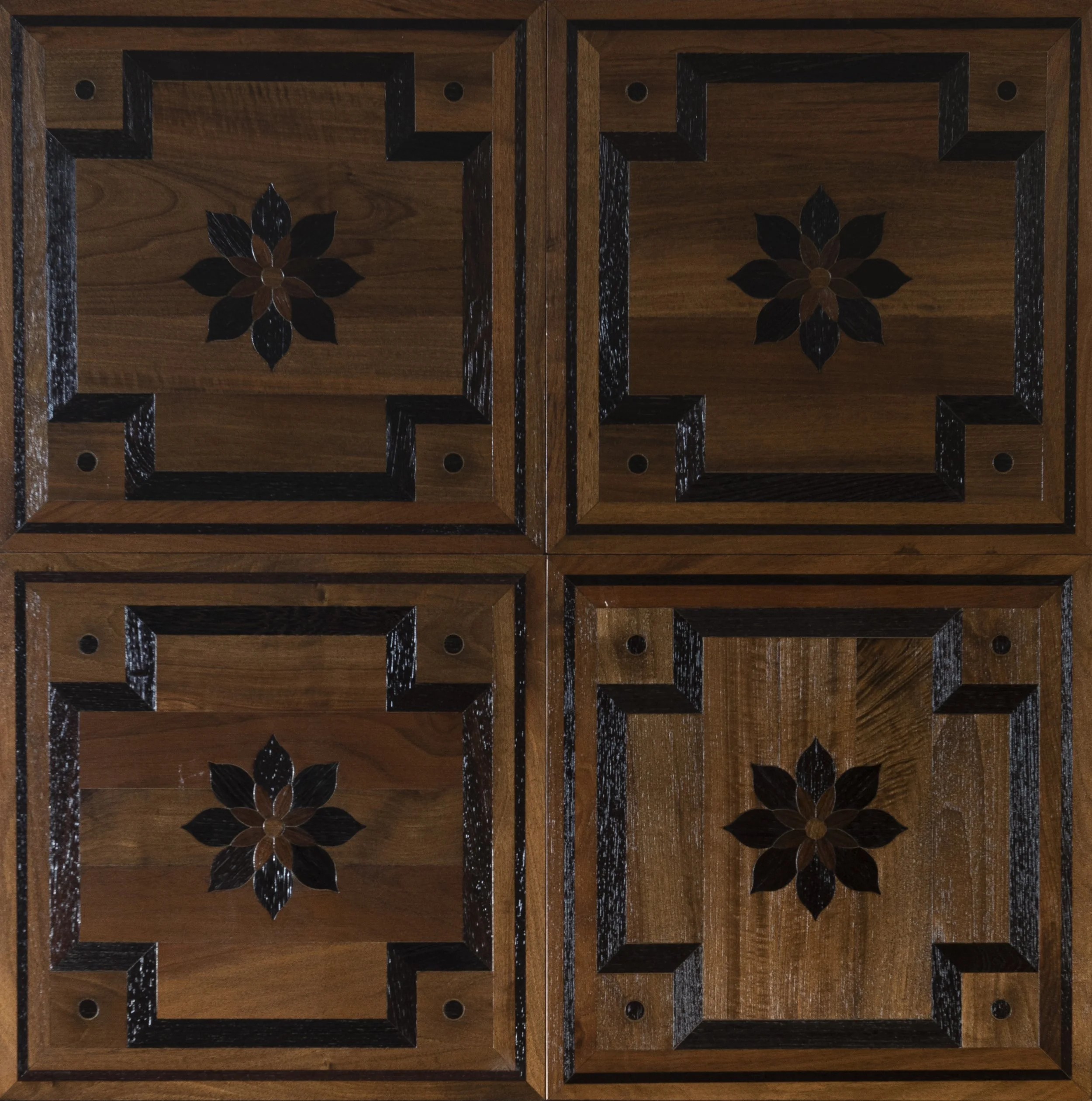 Cuatro losetas de cuadros de madera con diseño de flor en el centro, formando un patrón cuadrado.