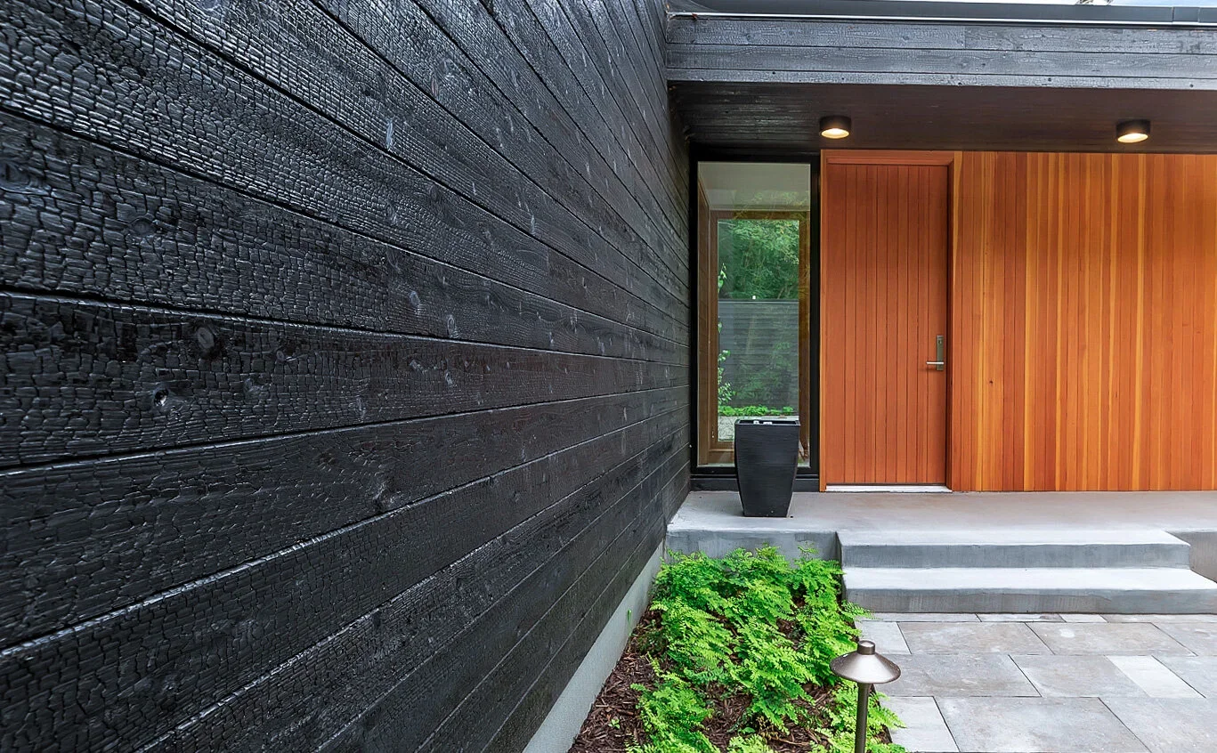 Dos jarrones de cerámica beige, uno con flores secas y el otro vacío, en un fondo gris