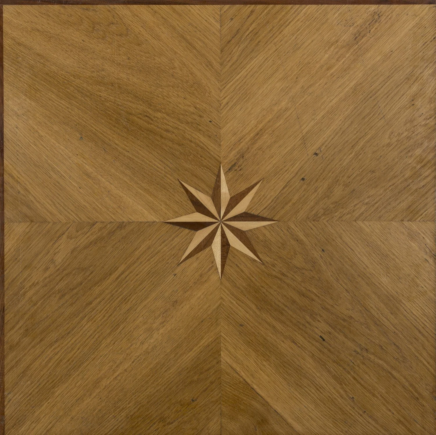 Madera color café con una estrella de mármol en el centro, diseño en patrón simétrico.