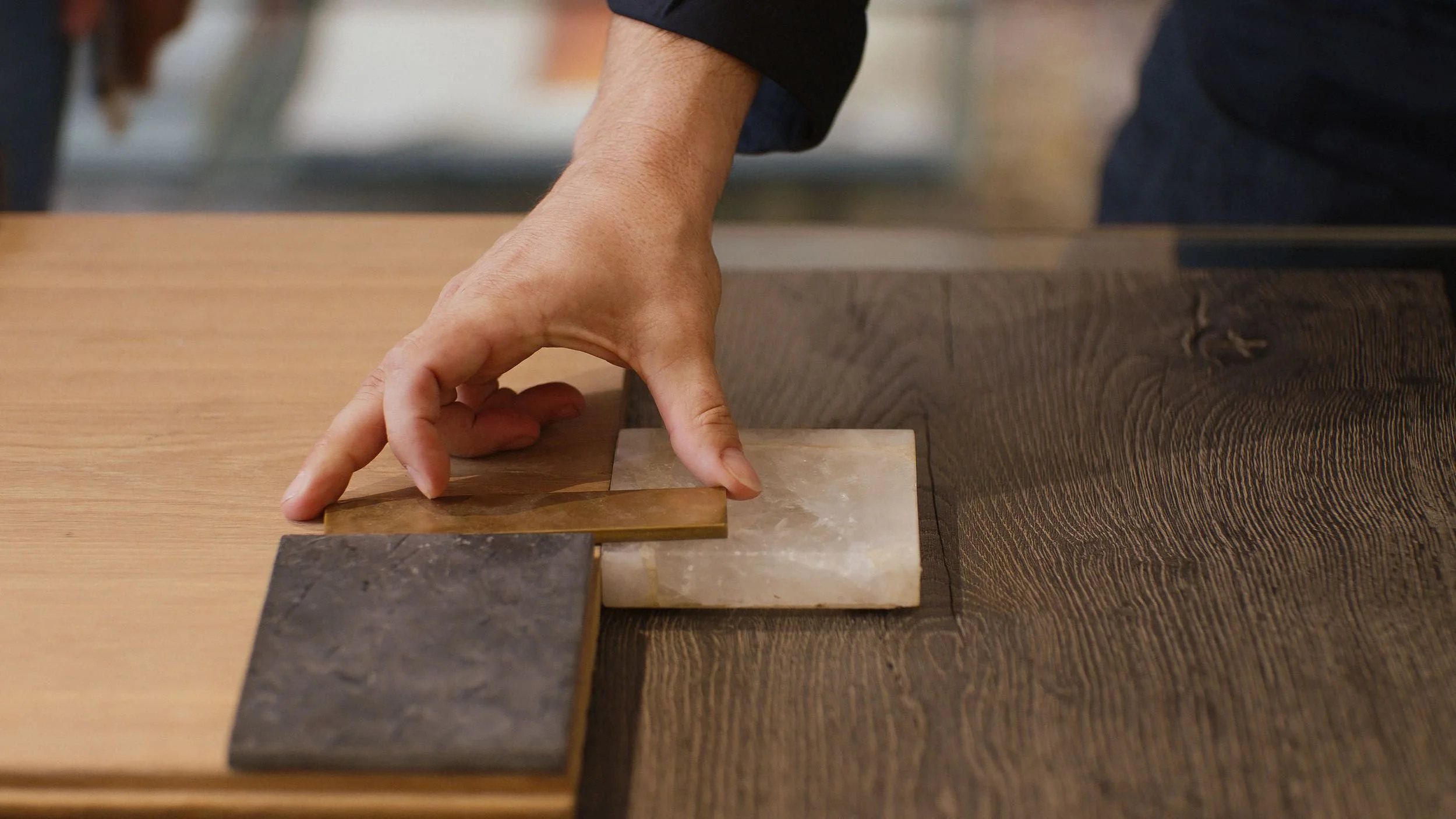 Una mano ajustando tablas de madera y piedra en una mesa de trabajo.