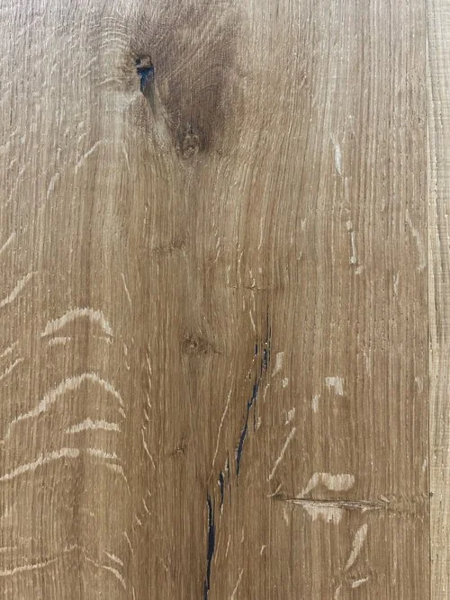 Madera clara con nudos y una grieta negra en el centro.