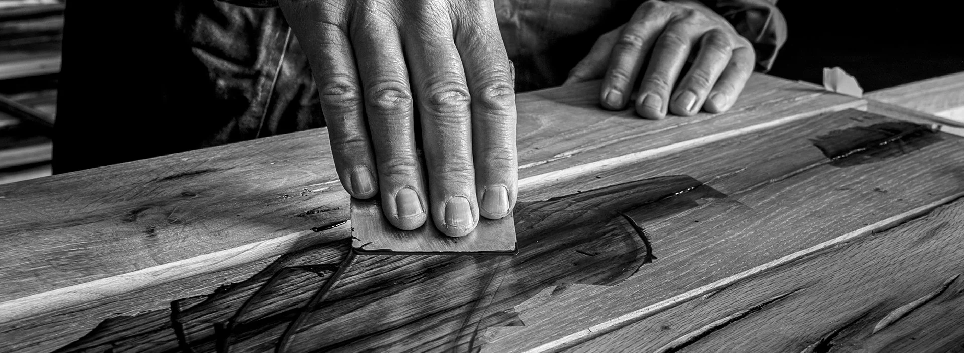 Manos lijando una superficie de madera con lija.