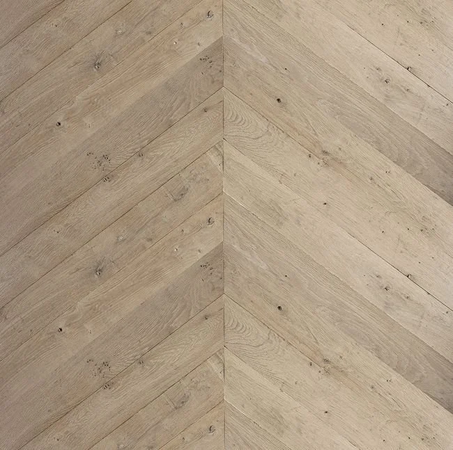 Piso de madera con patrón de espiga o chevrón en tonos beige claros.