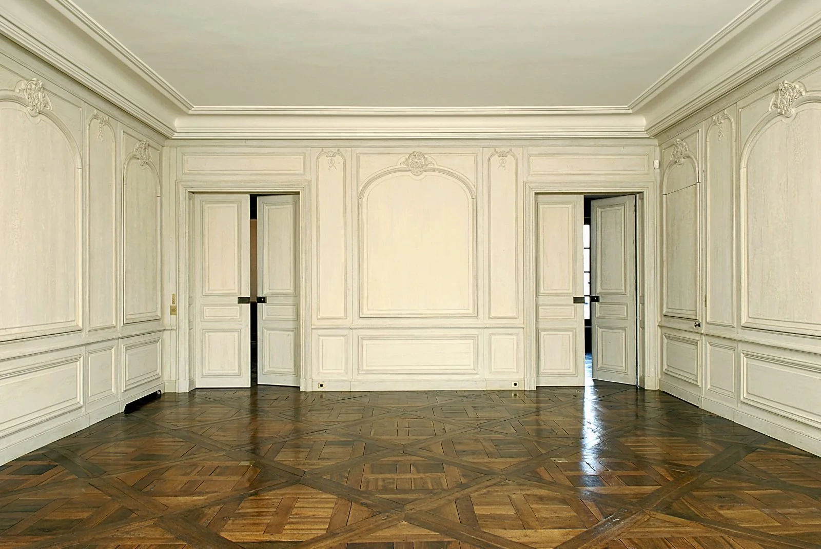 Sala elegante con paredes blancas con molduras de madera y suelo de parquet en estilo clásico.