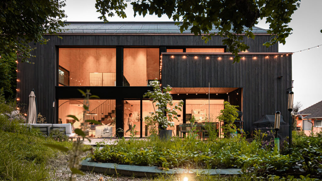 Jarrón de cerámica con flor seca en una superficie de madera, con sombra y luz natural.