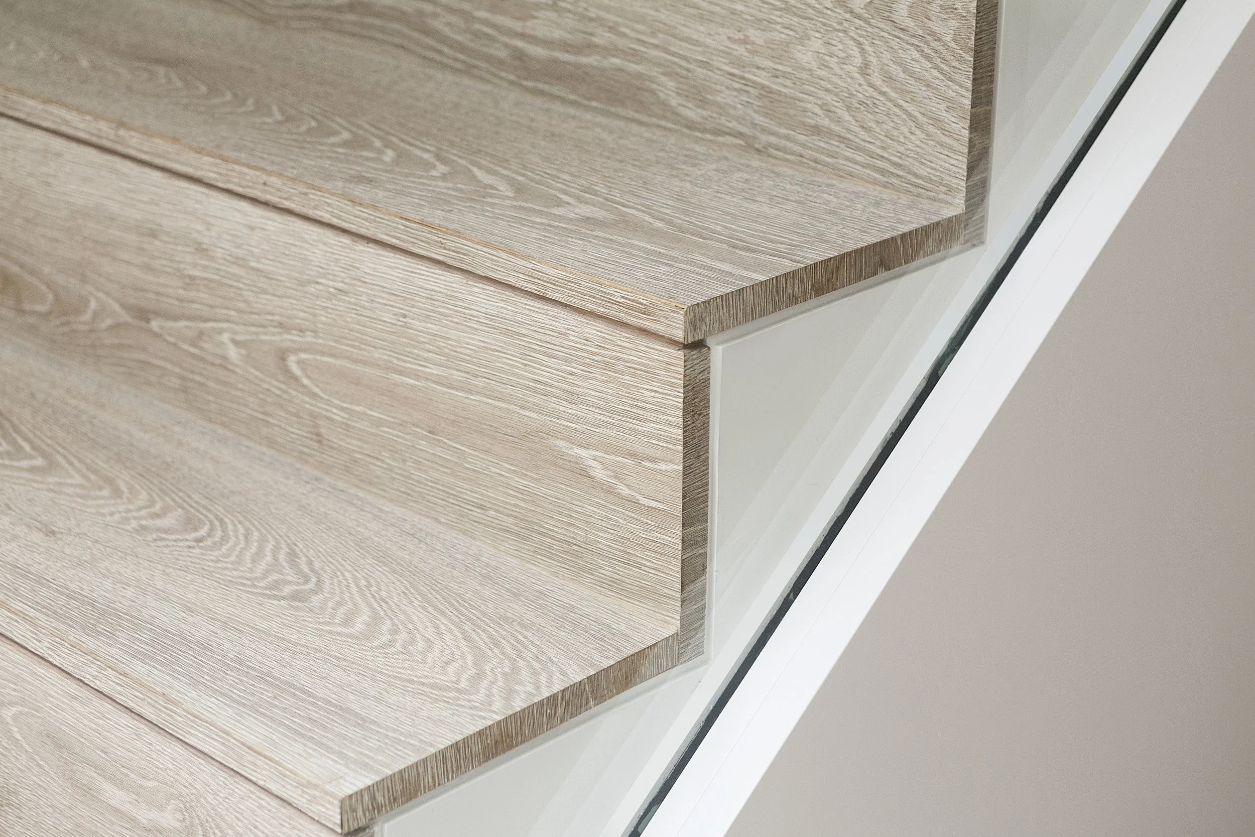 Escalera de madera de estilo moderno con estructura blanca y detalles de vidrio.