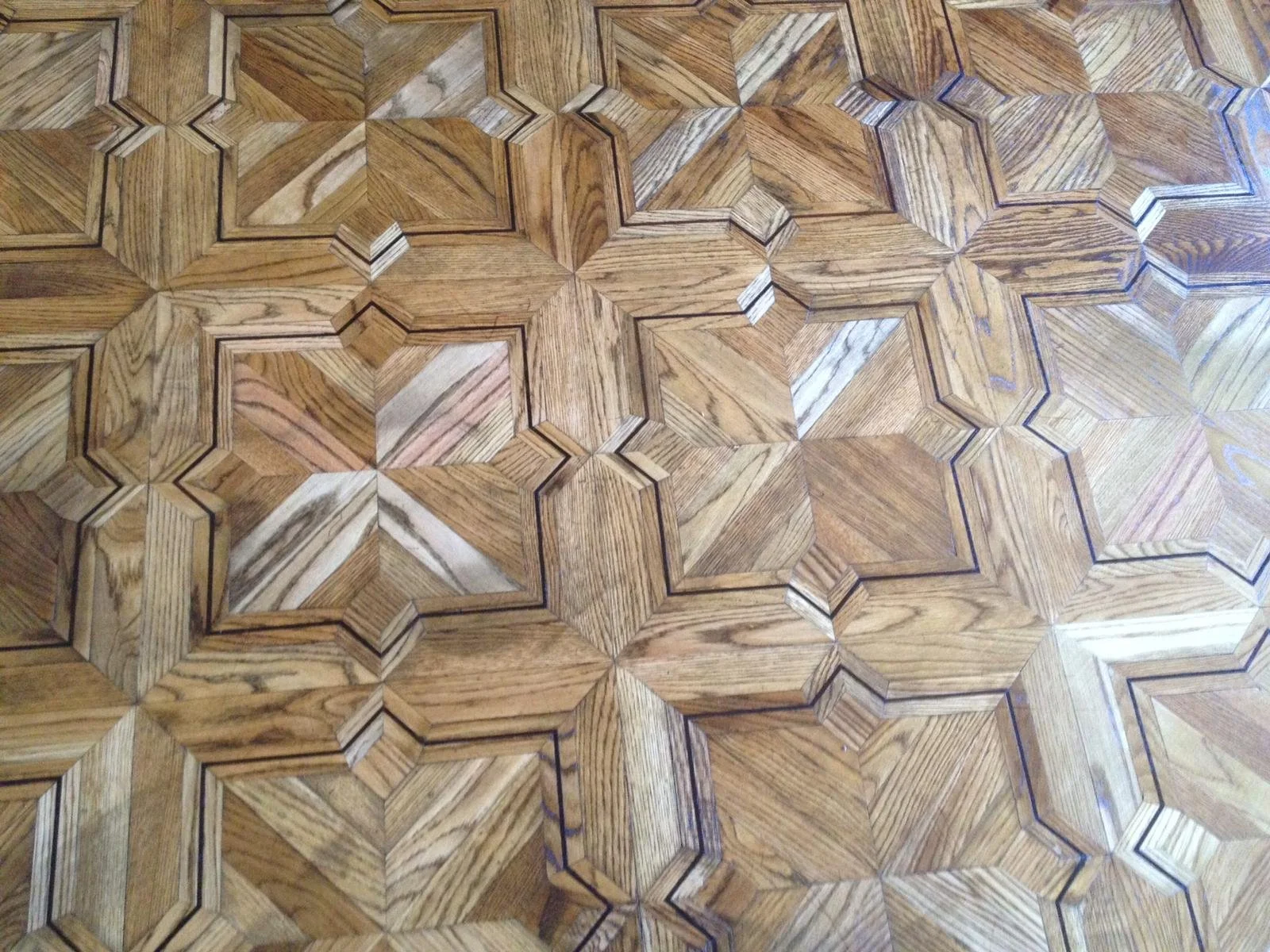 Pavimento de madera con patrón geométrico de hexágonos y líneas oscuras que delinean cada figura.