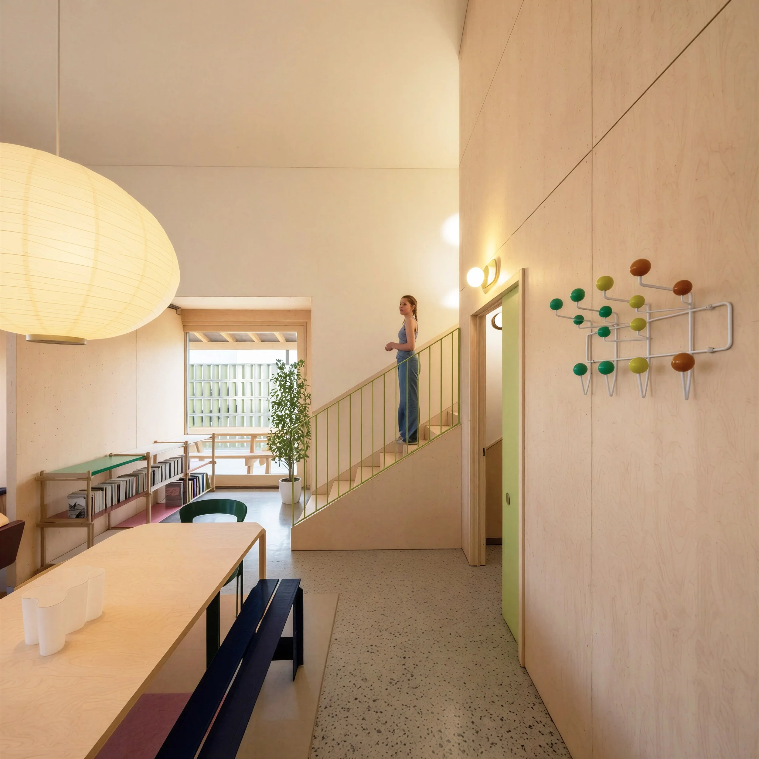 An image of an interior of an ADU with contemporary scandinavian style. HAY paper lamps, and Alvar Aalto furniture. Sage green colorful palette.