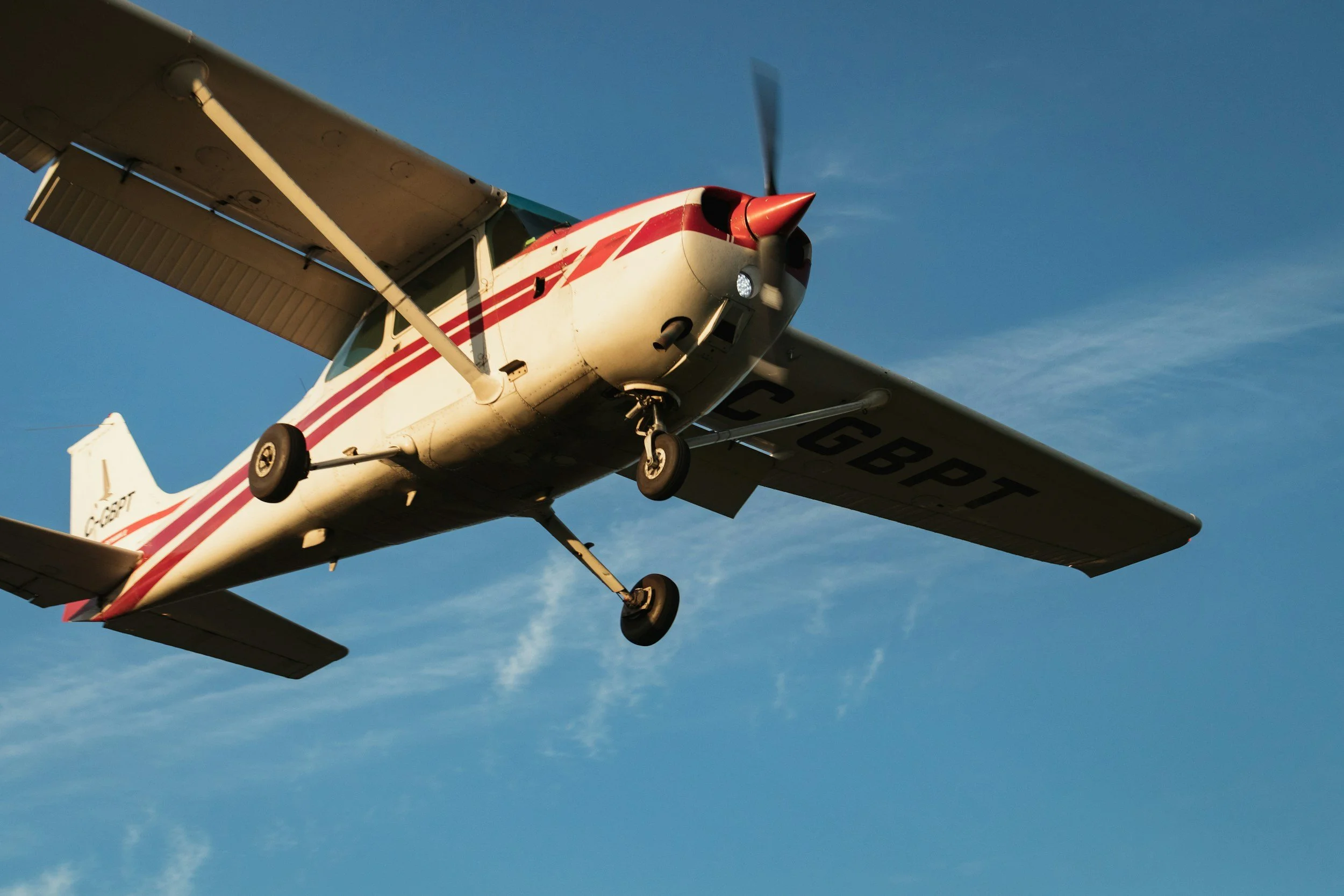 Small airplane flying against a blue sky with some clouds visible.