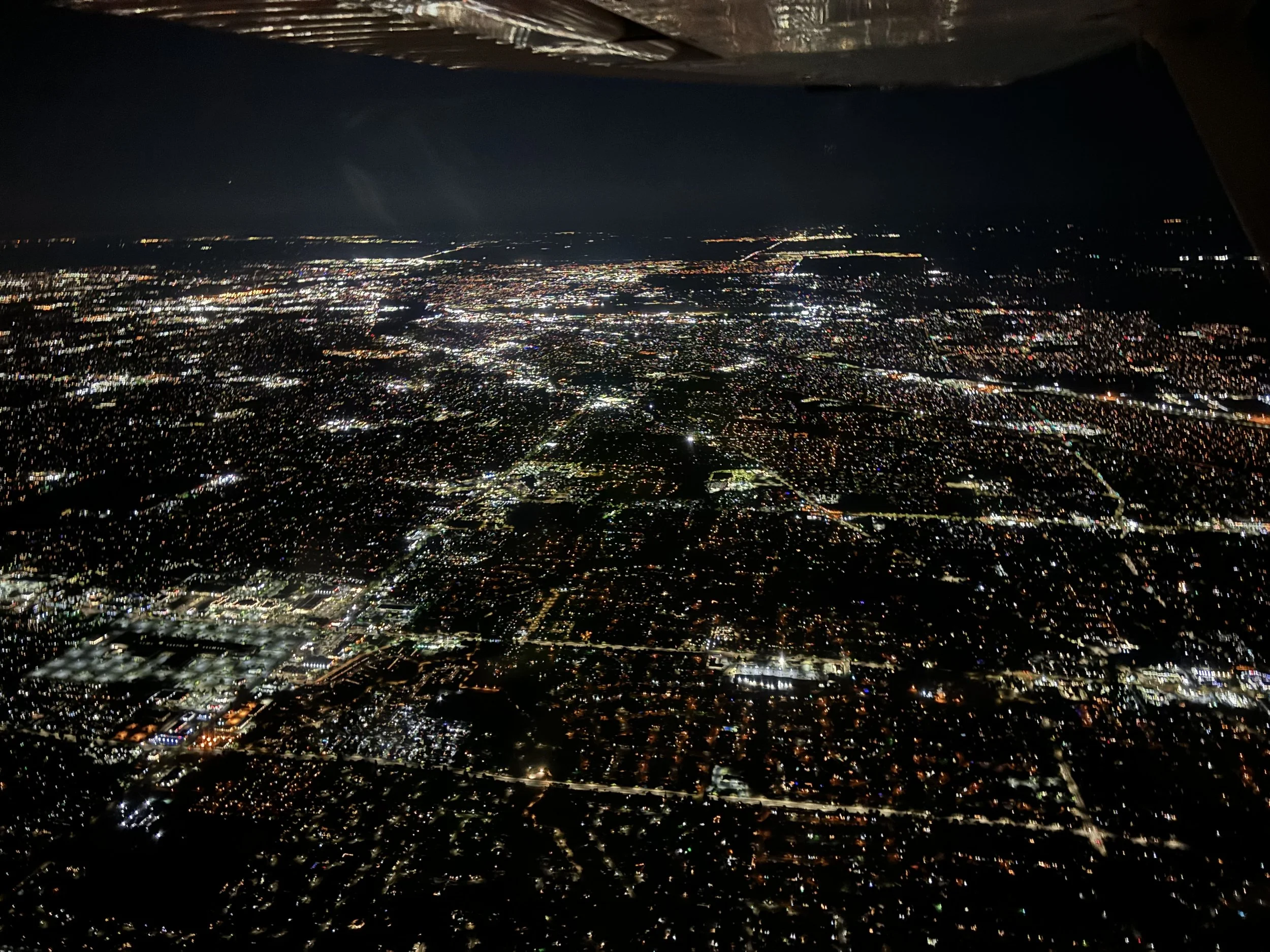 Nighttime aerial view of a sprawling city illuminated with countless lights from buildings and streets.