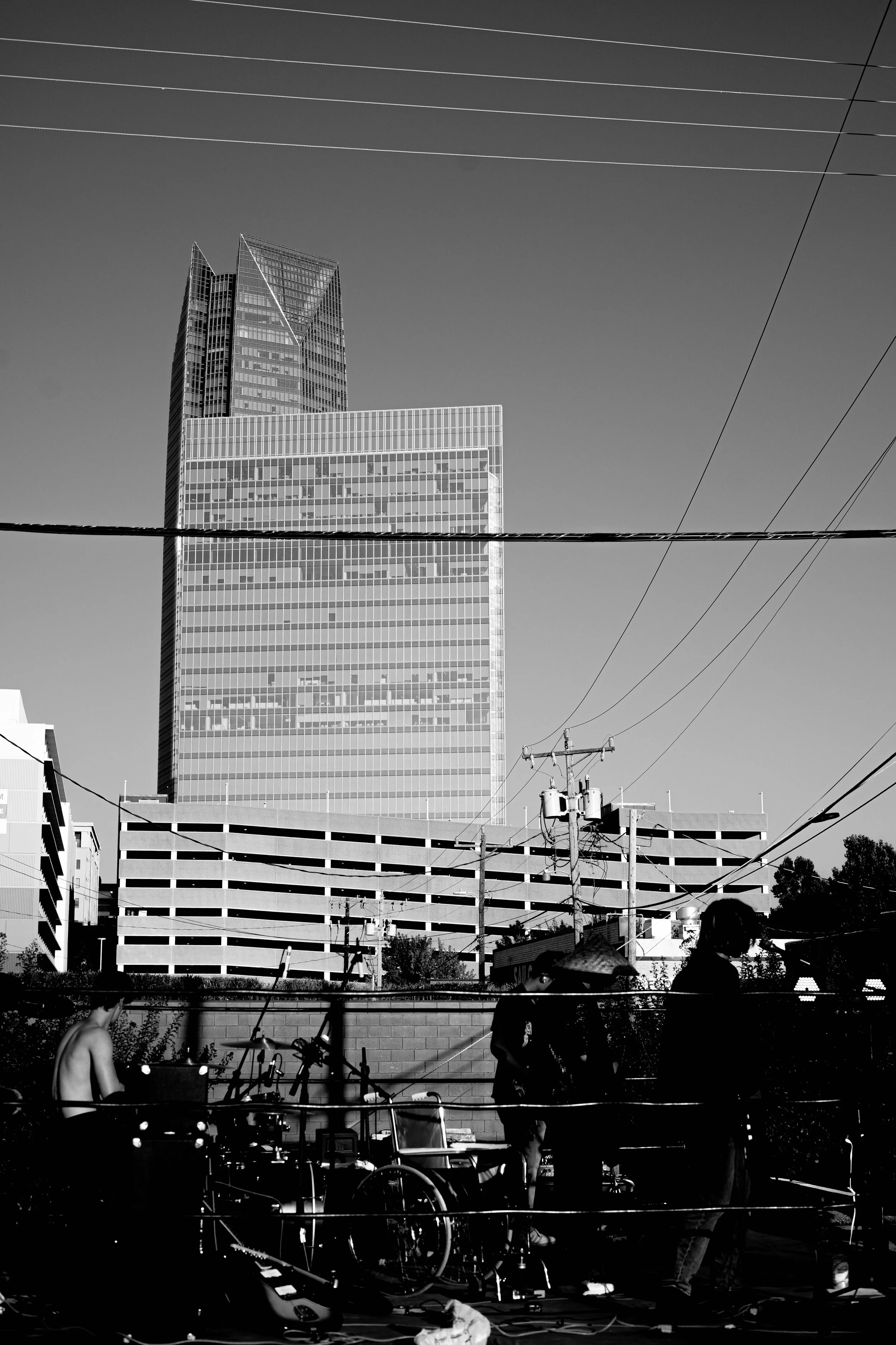 Black and white photo of a city skyline with a tall skyscraper and a group of people with bicycles in the foreground.
