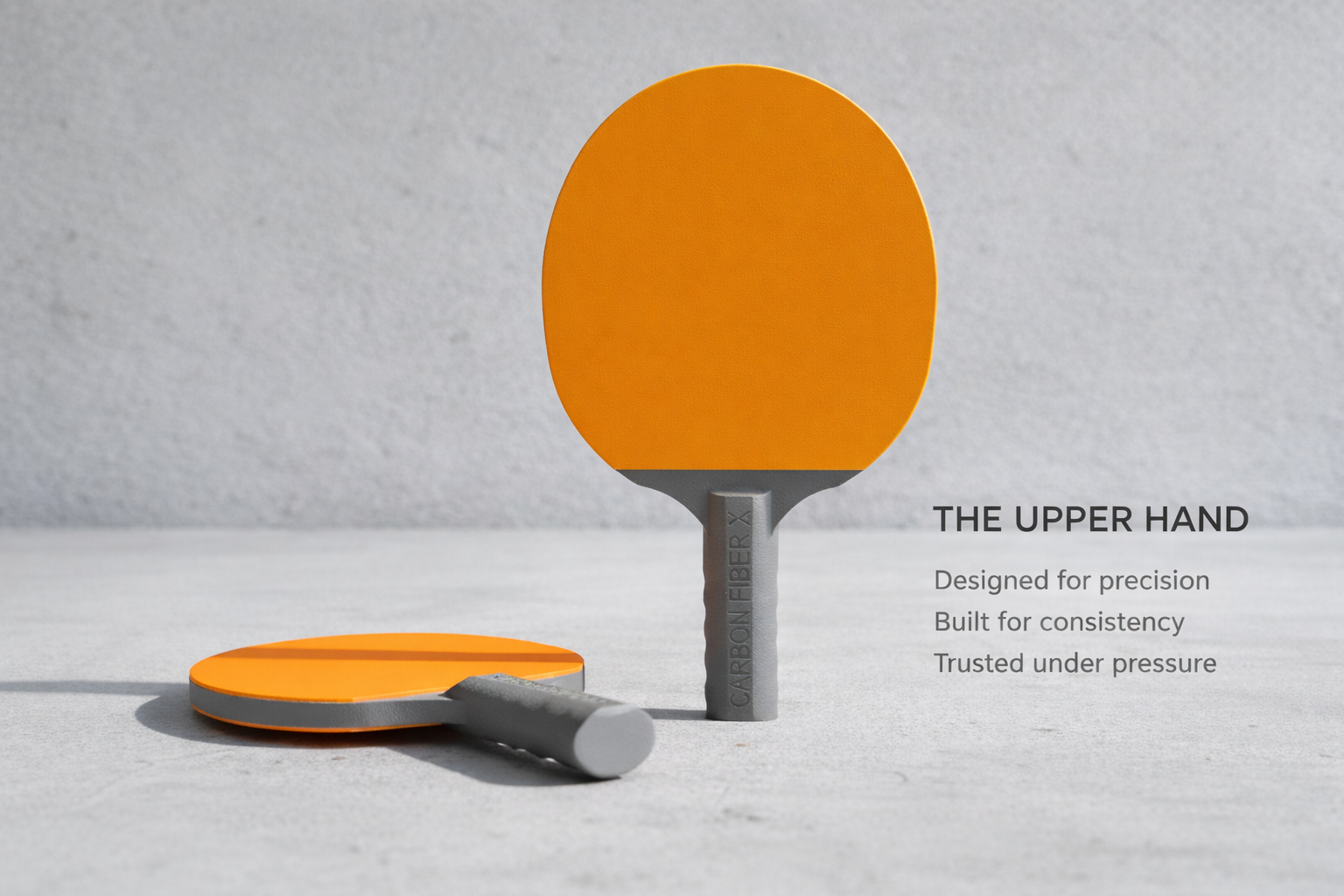 Two orange ping pong paddles with gray handles placed on a light gray surface, with one paddle standing upright and the other lying flat, against a textured gray background. Text on the image says "THE UPPER HAND" and lists characteristics: "Designed for precision," "Built for consistency," and "Trusted under pressure."