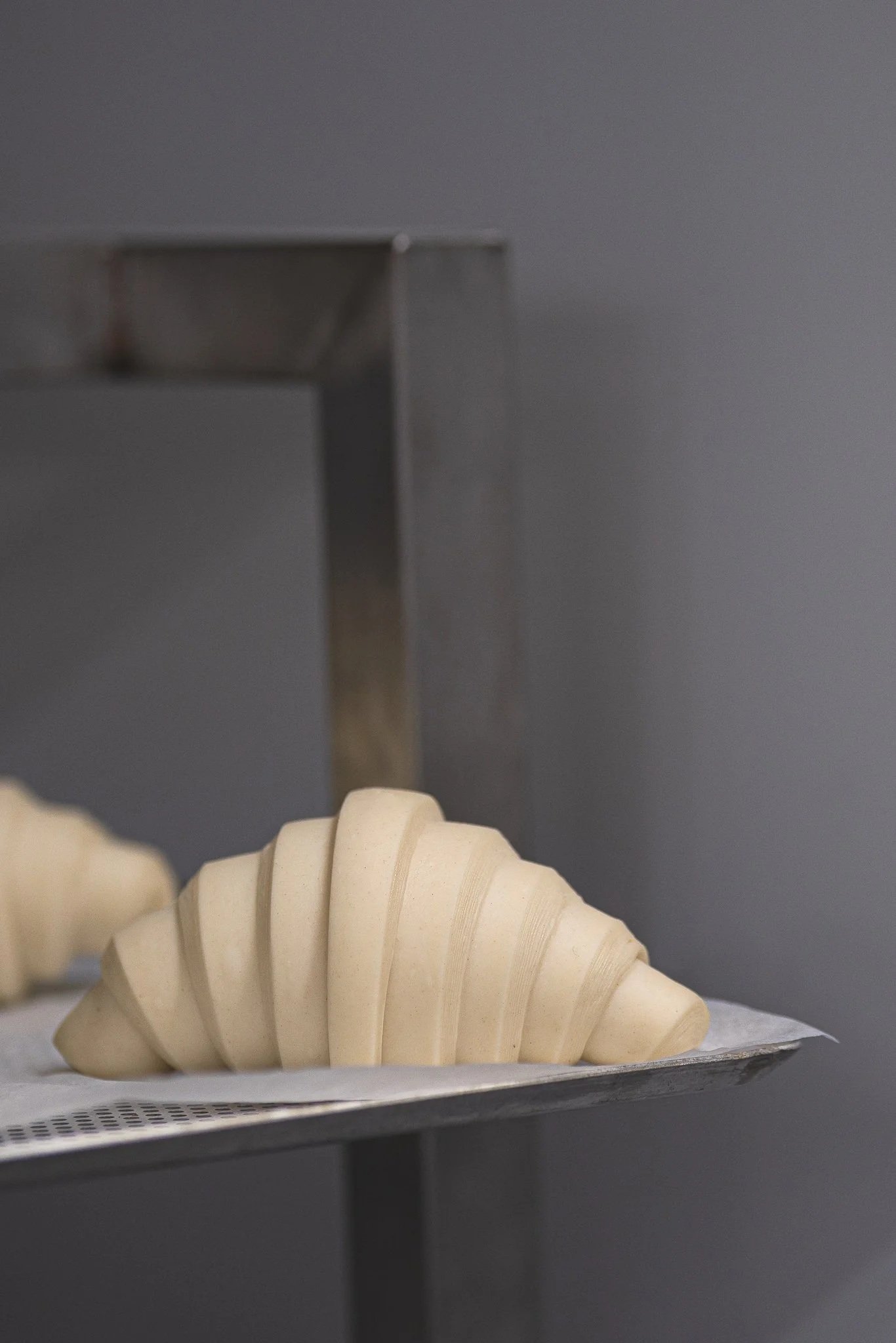 Un croissant colocado en una bandeja fermentado preparado para hornear.