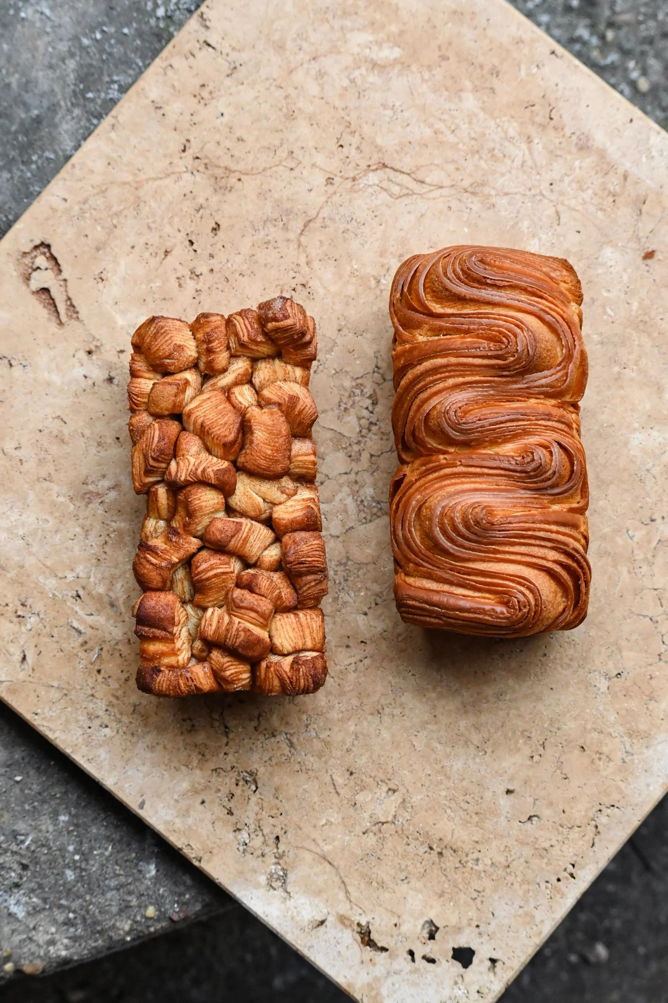 Dos piezas de bolleria en una bandeja brioche hojaldrado y monkey bread