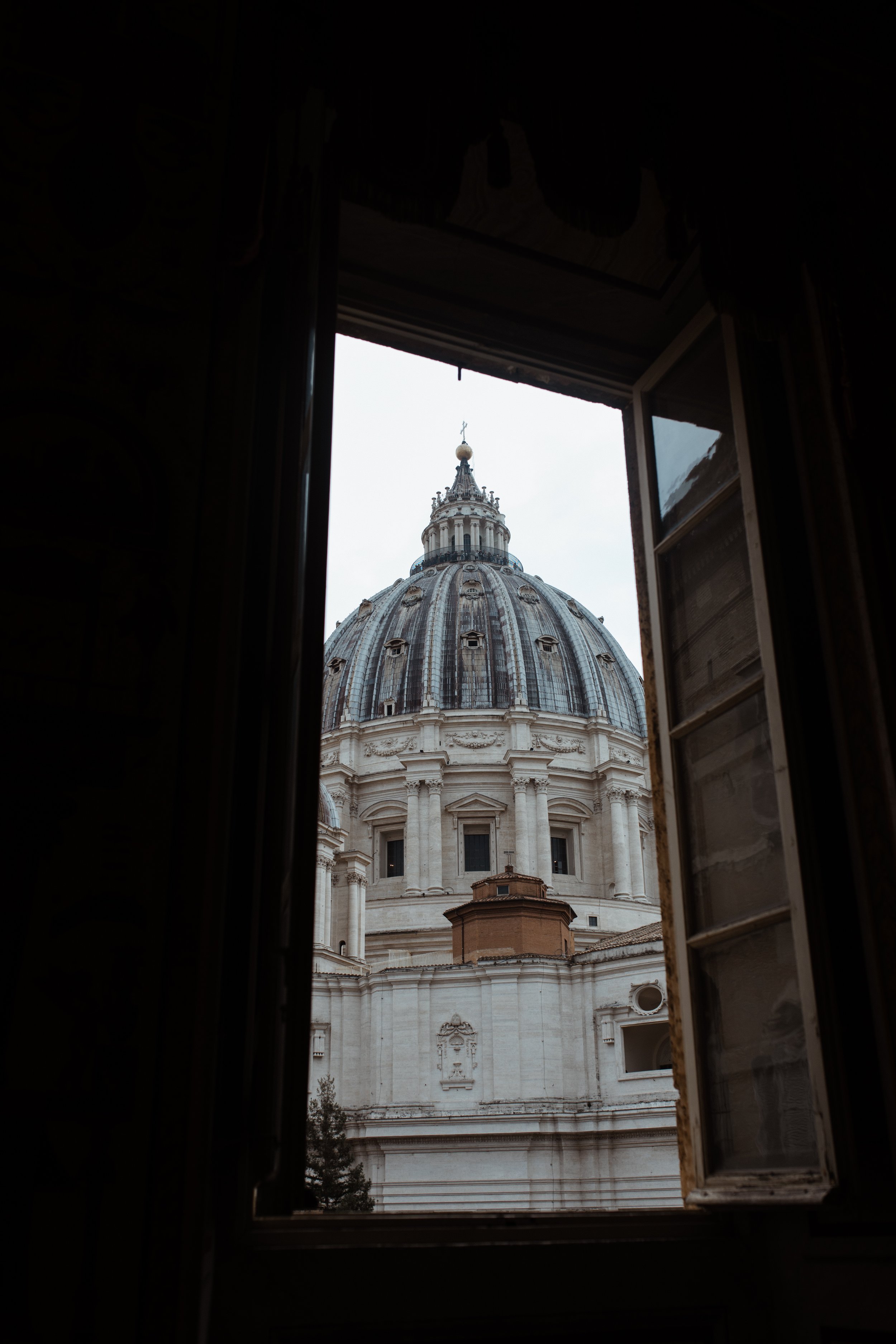 View of the dome of St. Peter's Basilica in Vatican City, seen through a window.