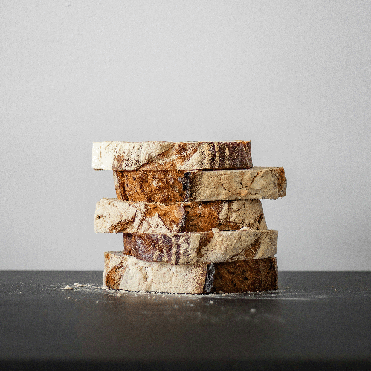 Stacked slices of petrified wood on a dark surface against a light gray background.