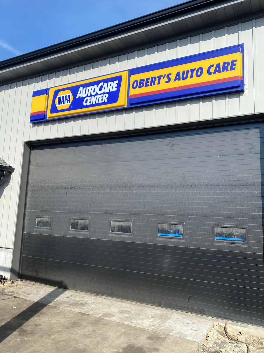 Storefront with NAPA AutoCare Center sign and Obert's Auto Care sign above a large gray garage door.