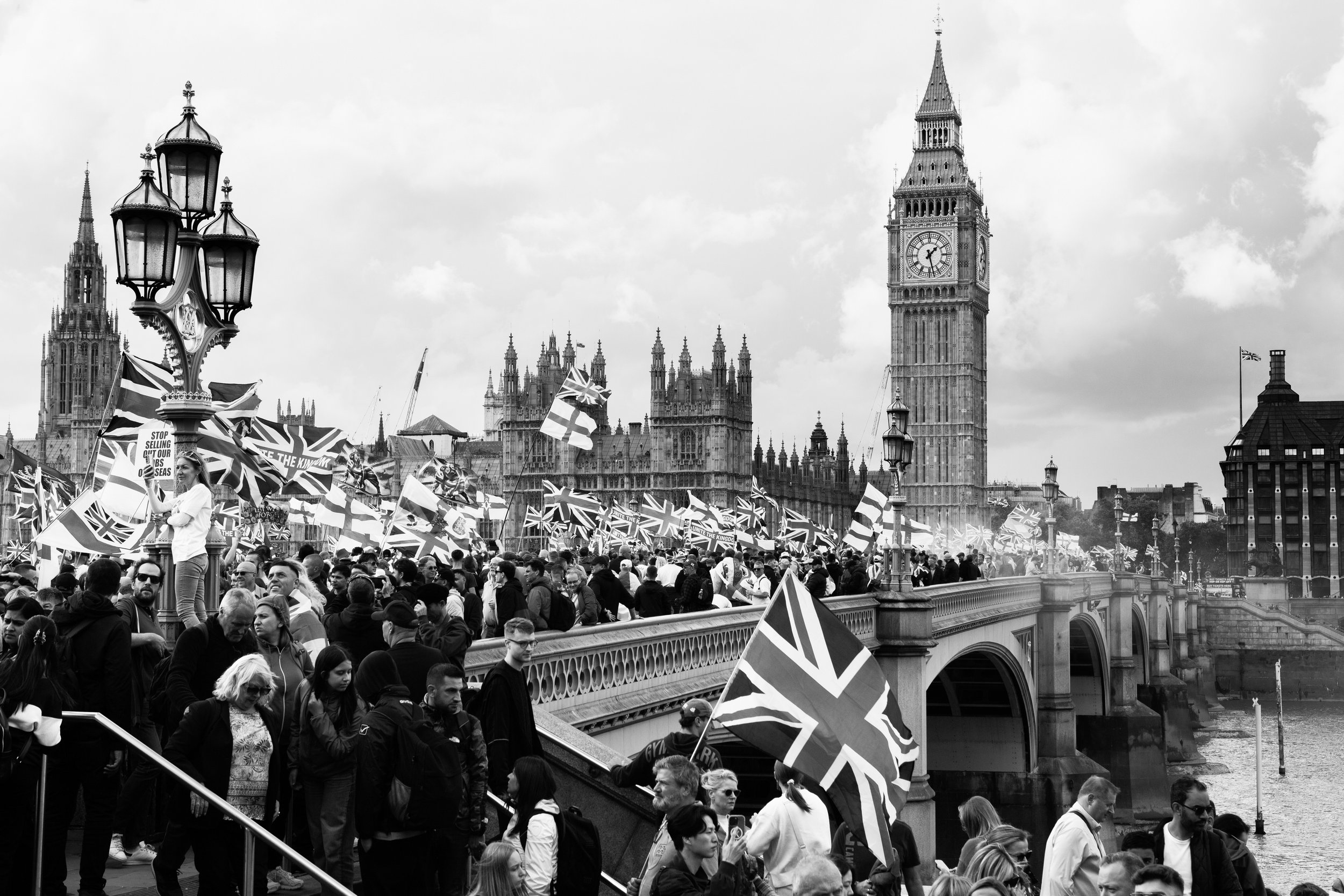 Crowd of protesters holding Union Jack flags near the Westminster Bridge and Big Ben in London.