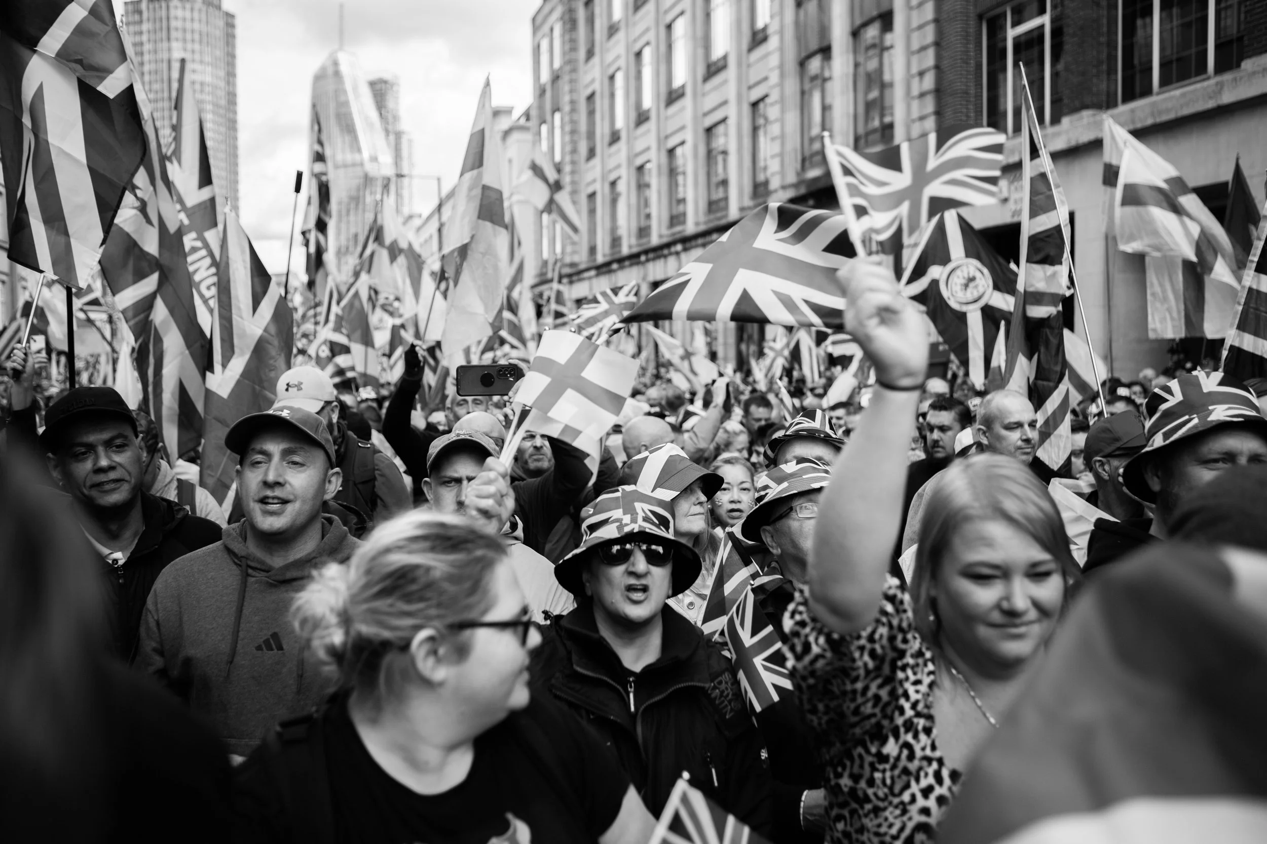 Crowd of people holding UK flags during a protest or celebration on a city street.