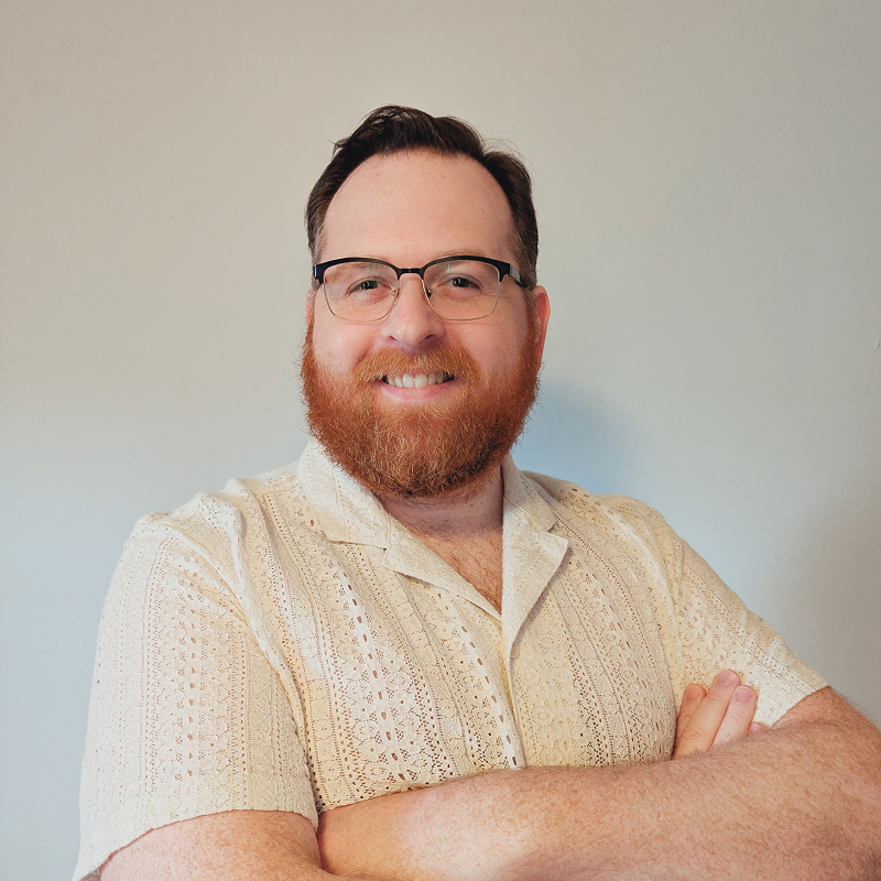 Portrait of Alex Davidson with his arms crossed and smiling at the camera