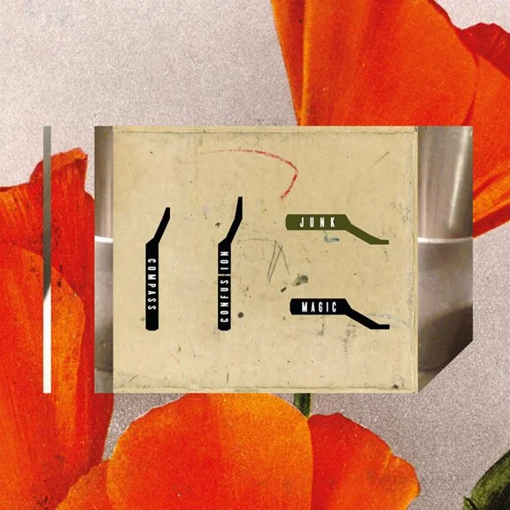 A vintage metal box with black labels saying 'Compass', 'Coin', 'Magic', and 'Junk', placed on a surface surrounded by red and orange flower petals.