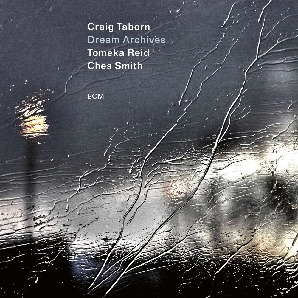Text overlay on a textured, rainy window obscuring a cityscape with streetlights at night. The text lists five names and a record label: Craig Taborn, Dream Archives, Tomeza Reid, Ches Smith, ECM.