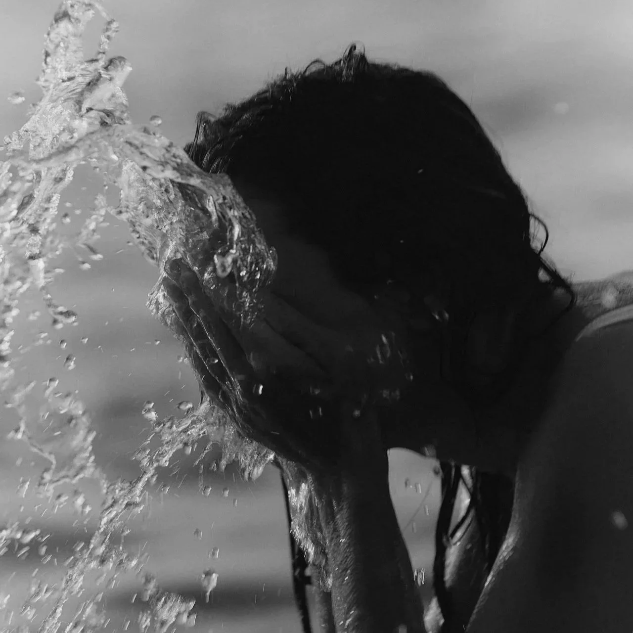 Person under water covering their face with water splashing around.
