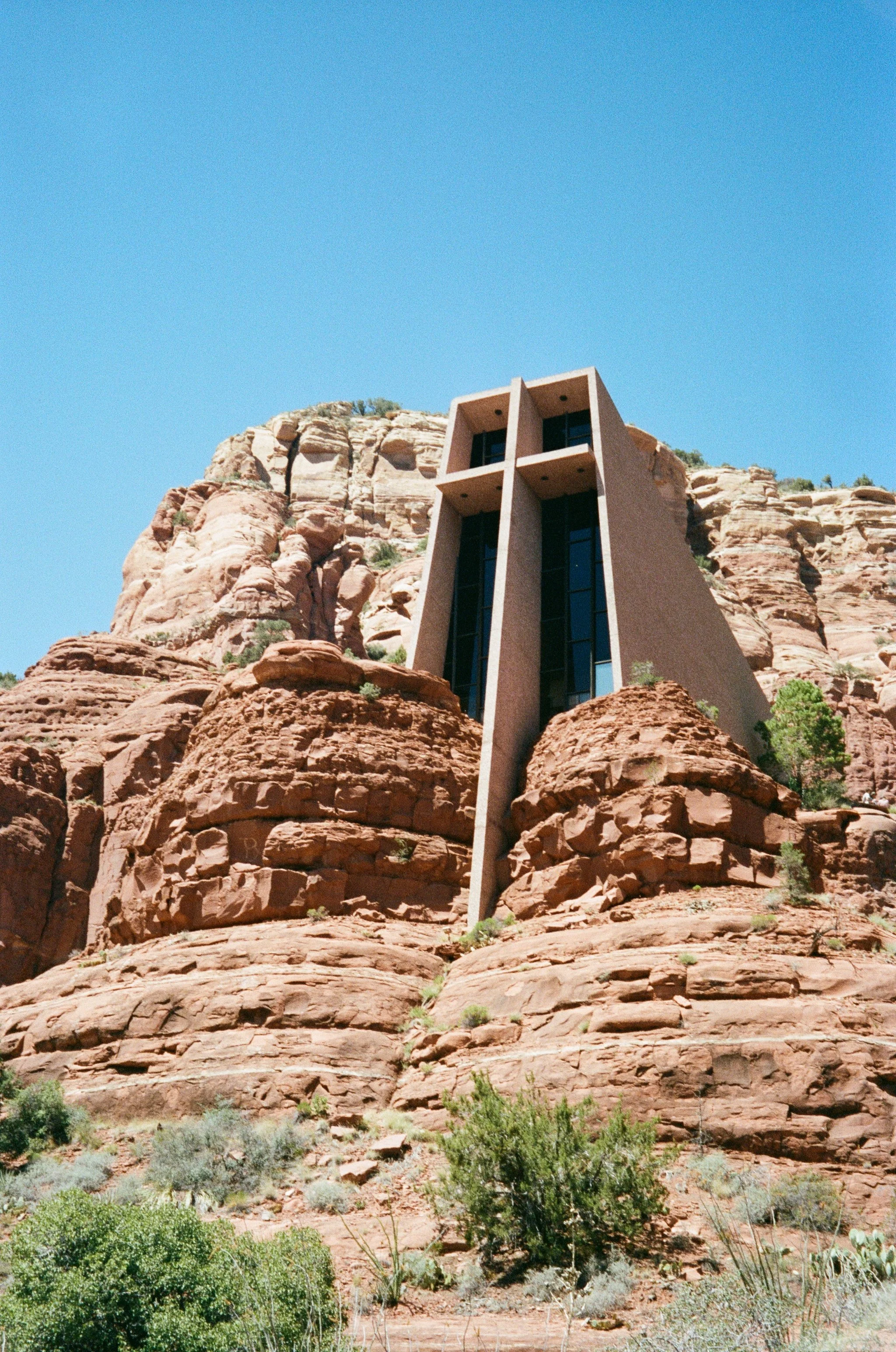 Modern building with vertical windows built into red sandstone rock formations under a clear blue sky.