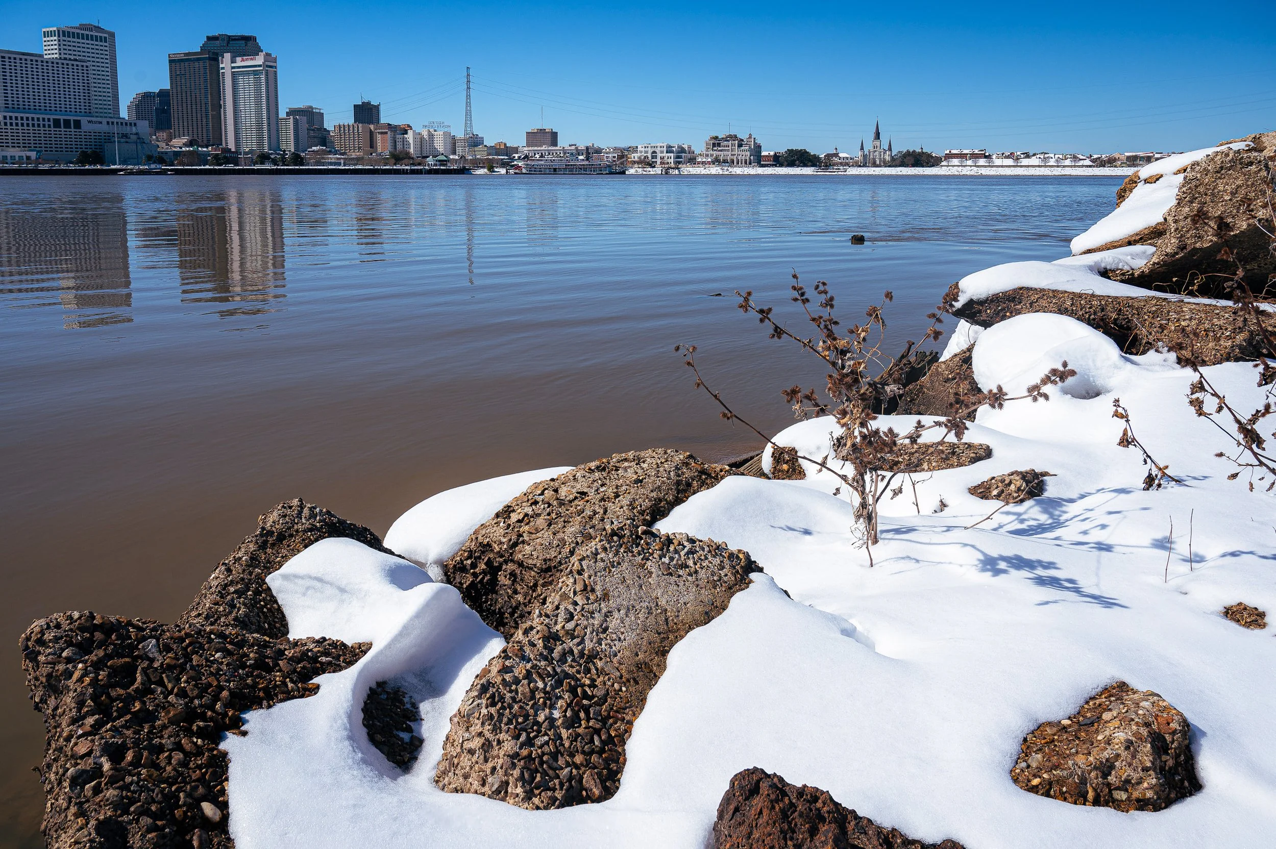 Fortuitous Winter

Rare snowfall along the Mississippi River in New Orleans, with snow-covered rocks in the foreground and the city skyline across the water.
