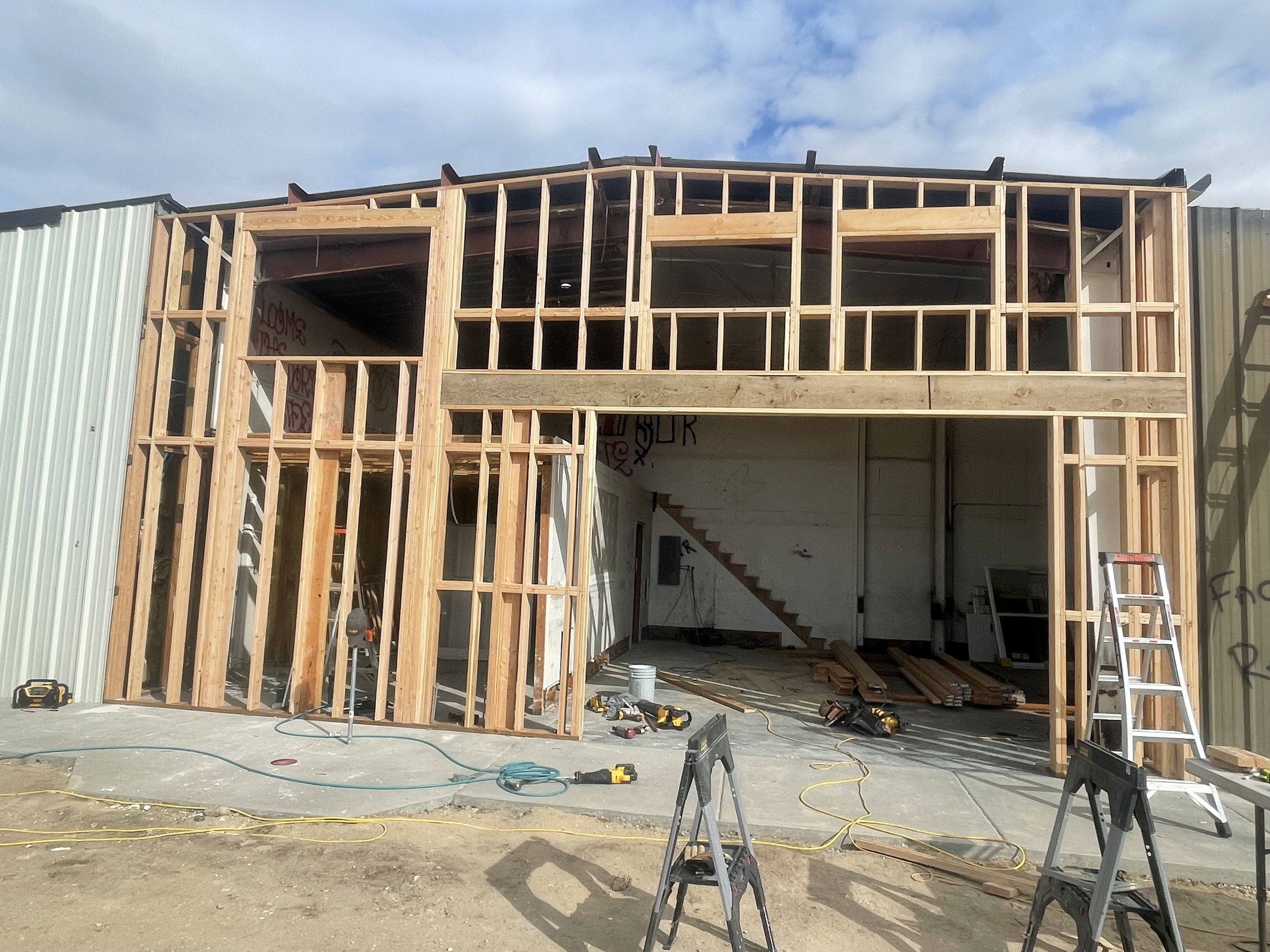 Construction site where a building with wooden framing is under construction, with tools and ladders visible.