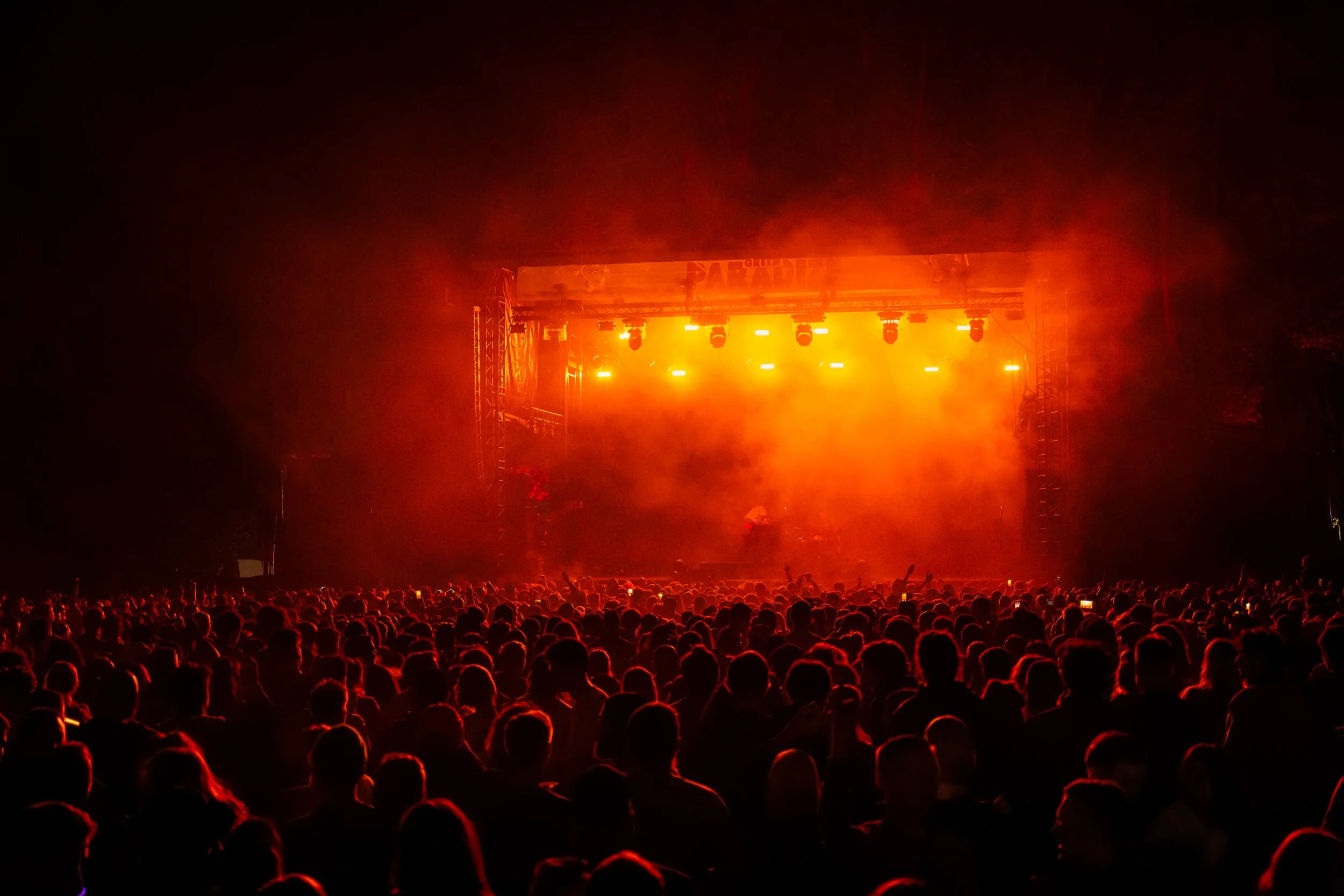 Une scène de concert avec un public nombreux et une scène éclairée en orange.