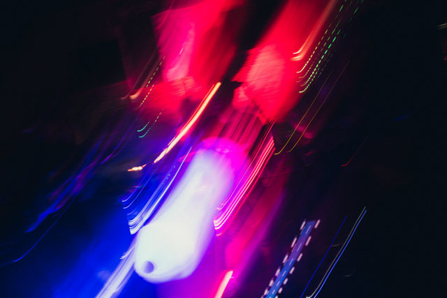 Blurred light streaks in neon pink, purple, blue, and green against a dark background.
