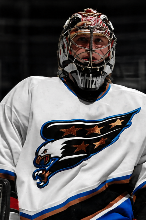 An ice hockey goalie wearing a white jersey with an eagle logo and a protective helmet.