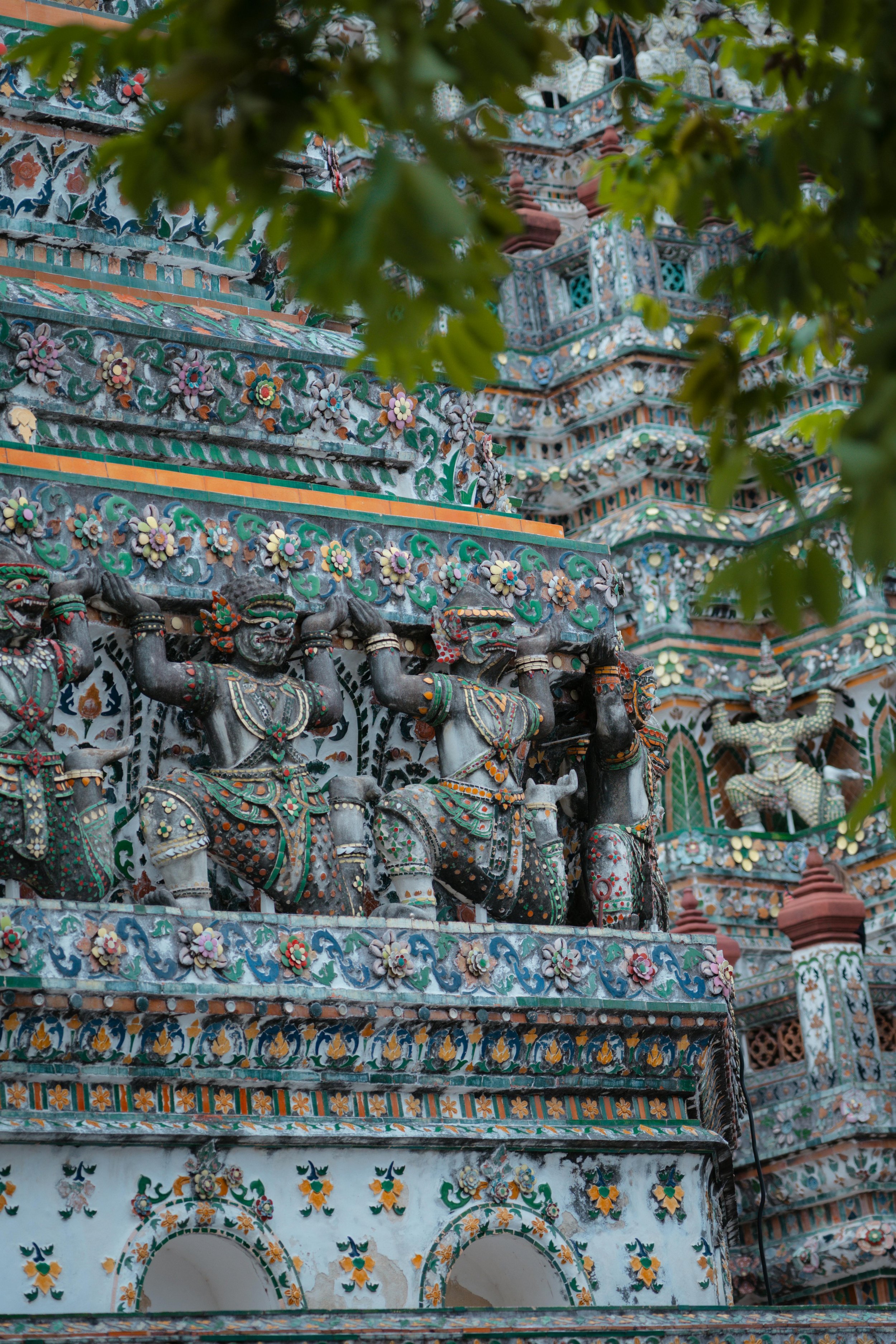 Close-up view of intricate colorful ceramic and sculpted details on a temple, featuring carved figures and decorative floral motifs.