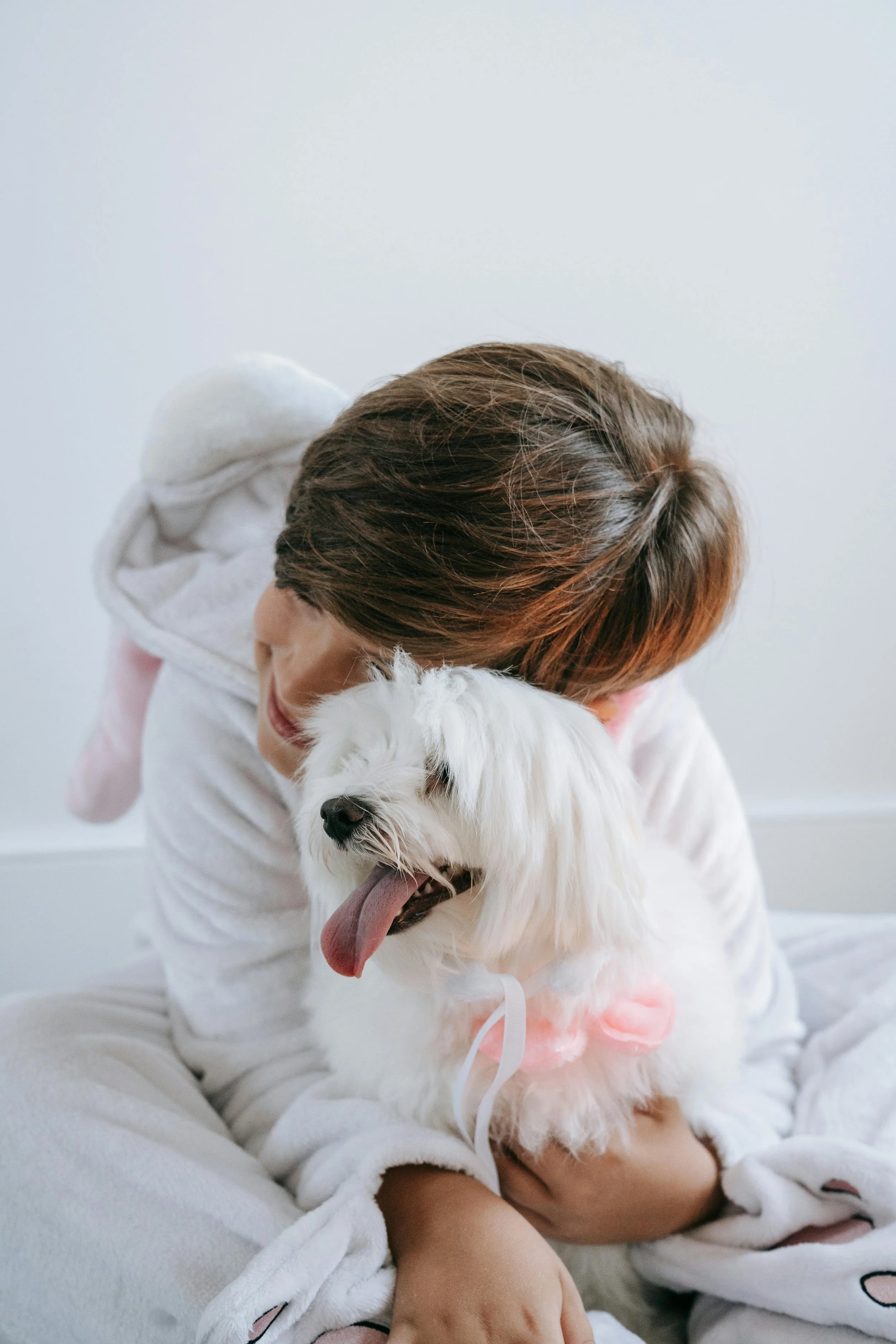 Person hugging a white dog with their eyes closed, both appearing happy and content.