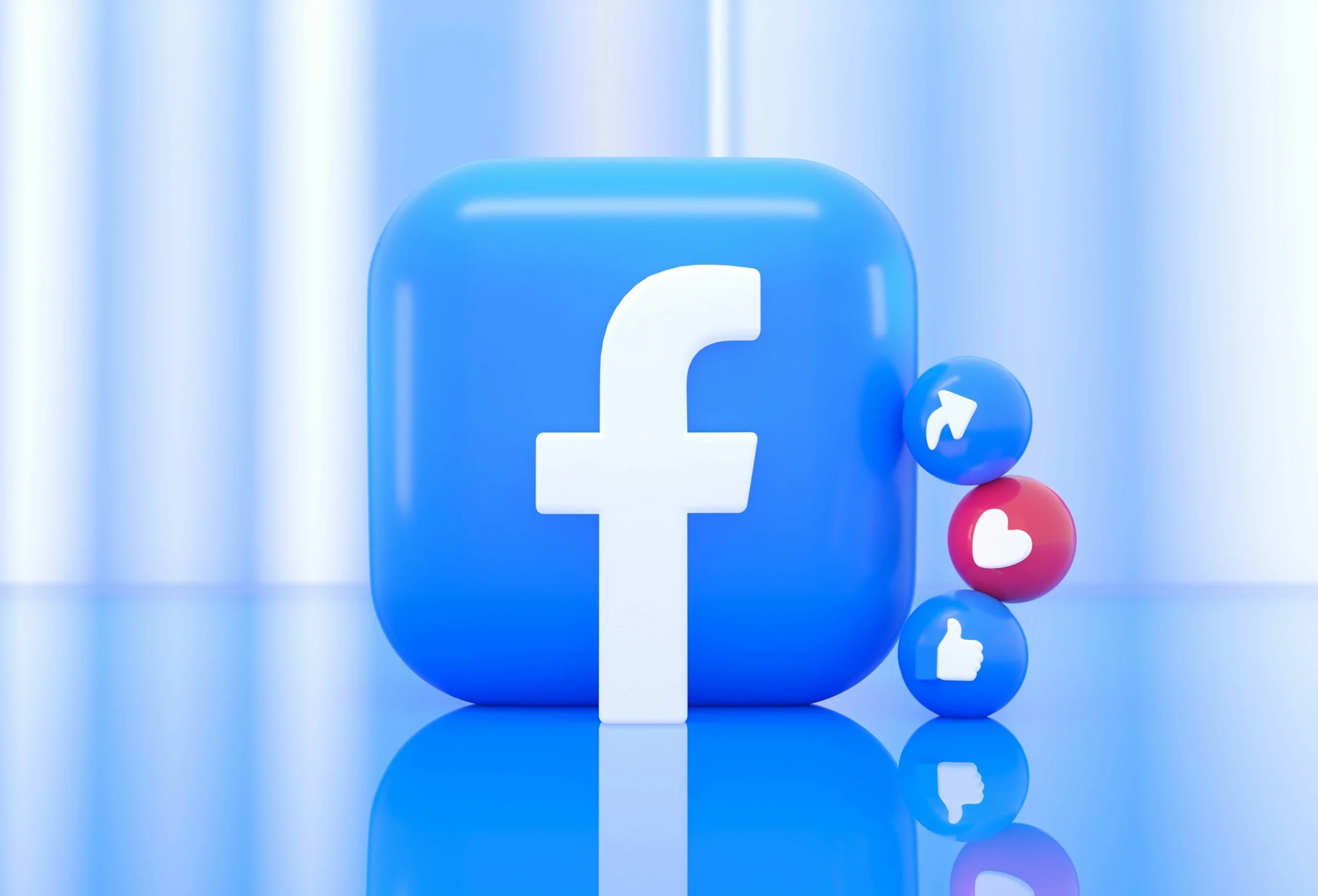 A large blue rectangular block with the white Facebook logo on it, accompanied by three smaller spheres with social media icons for Facebook, like, and share, all set against a reflective surface and light blue background.