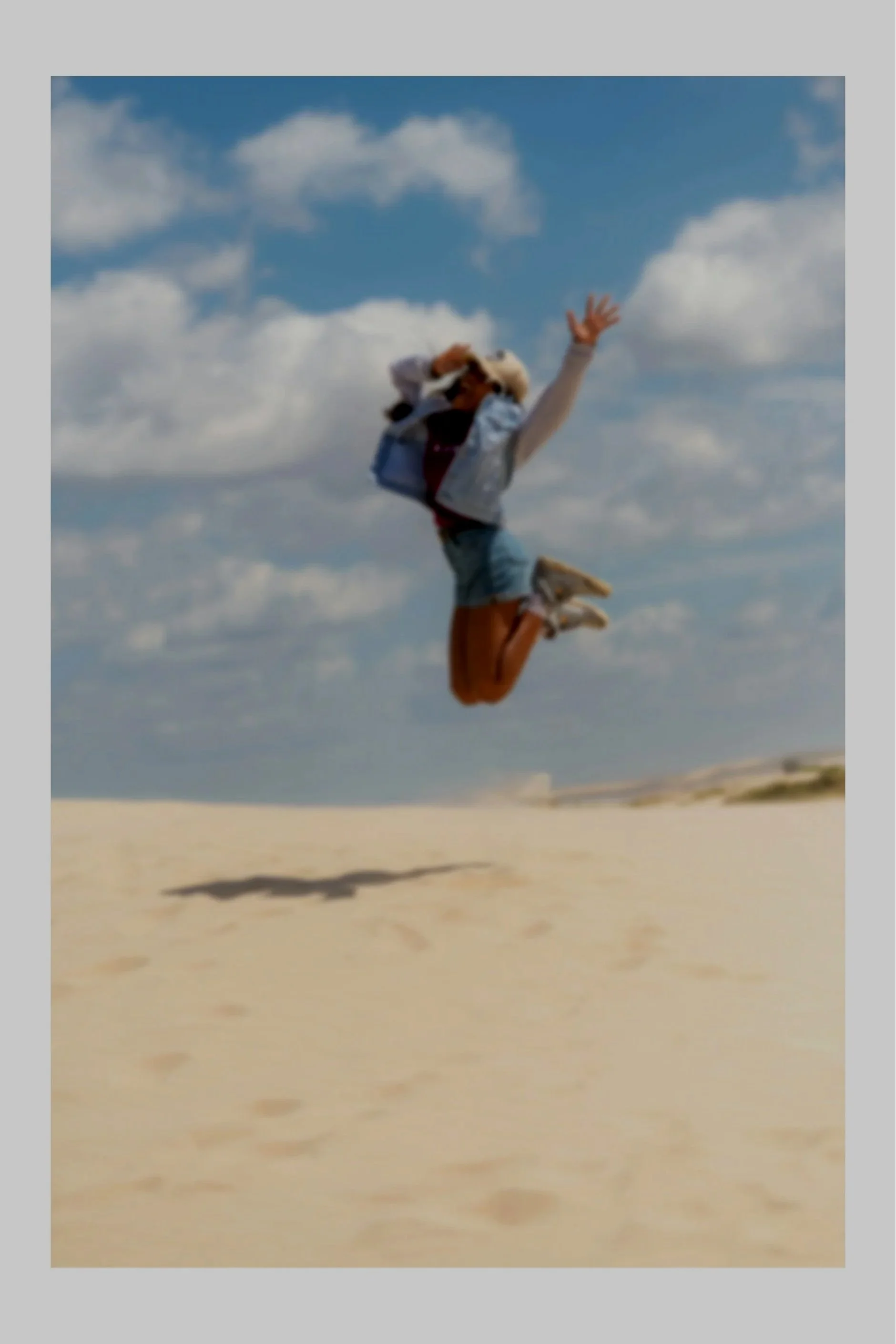 Woman jumping for joy on the sand at the beach.