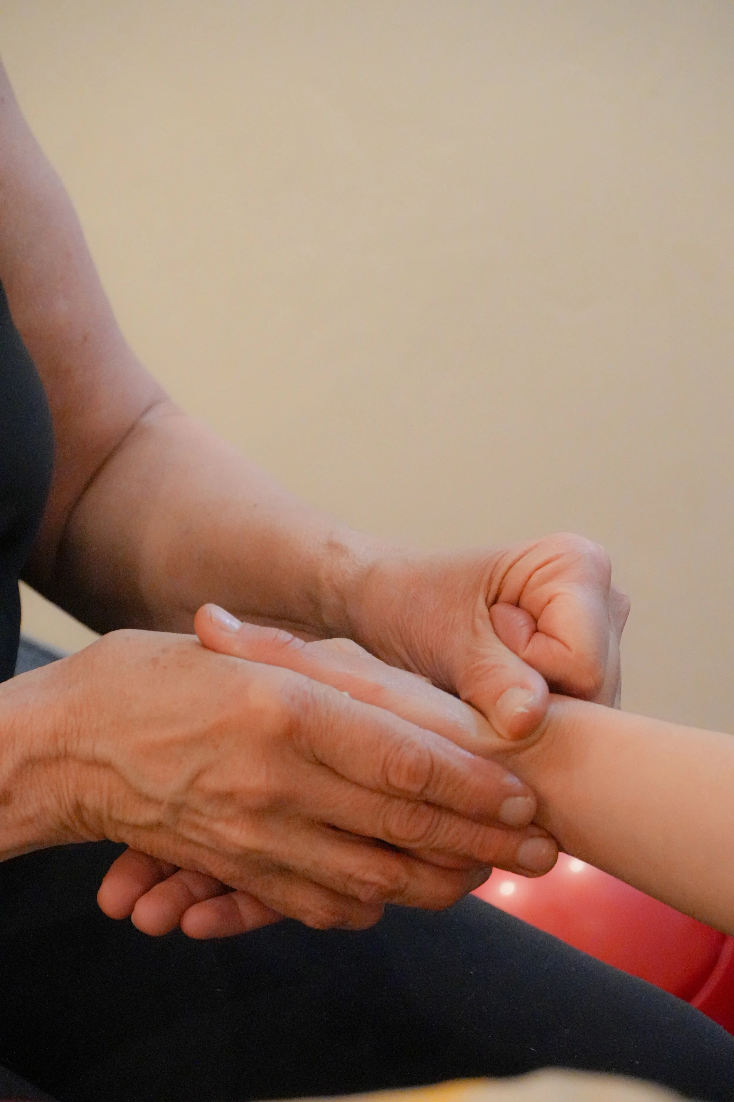 A person is giving a hand reflexology therapy to another individual, holding their arm gently with both hands.