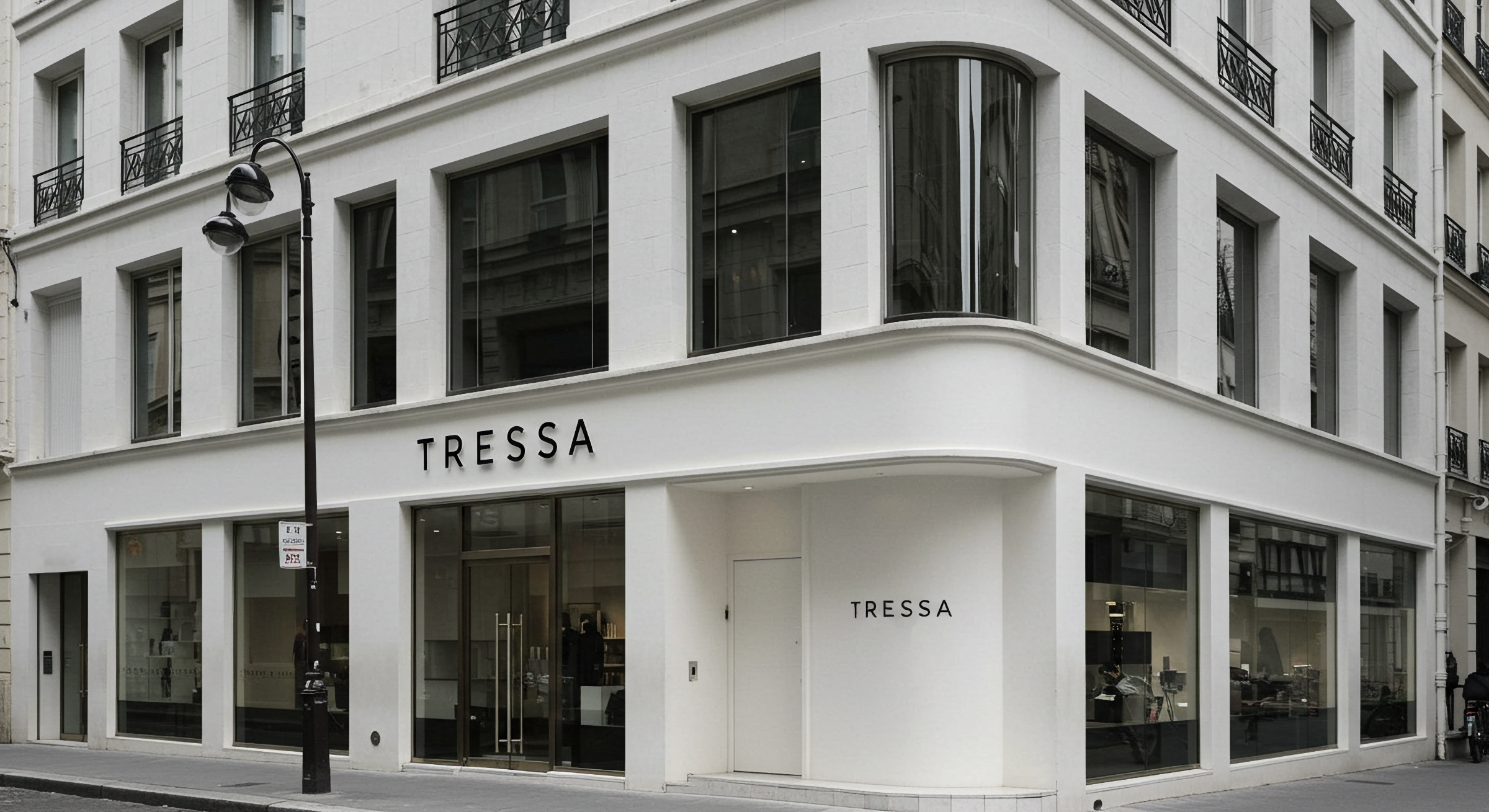 Exterior of a white building with large glass windows, black balconies, and a sign that reads "TRESSA" on the front and side walls.
