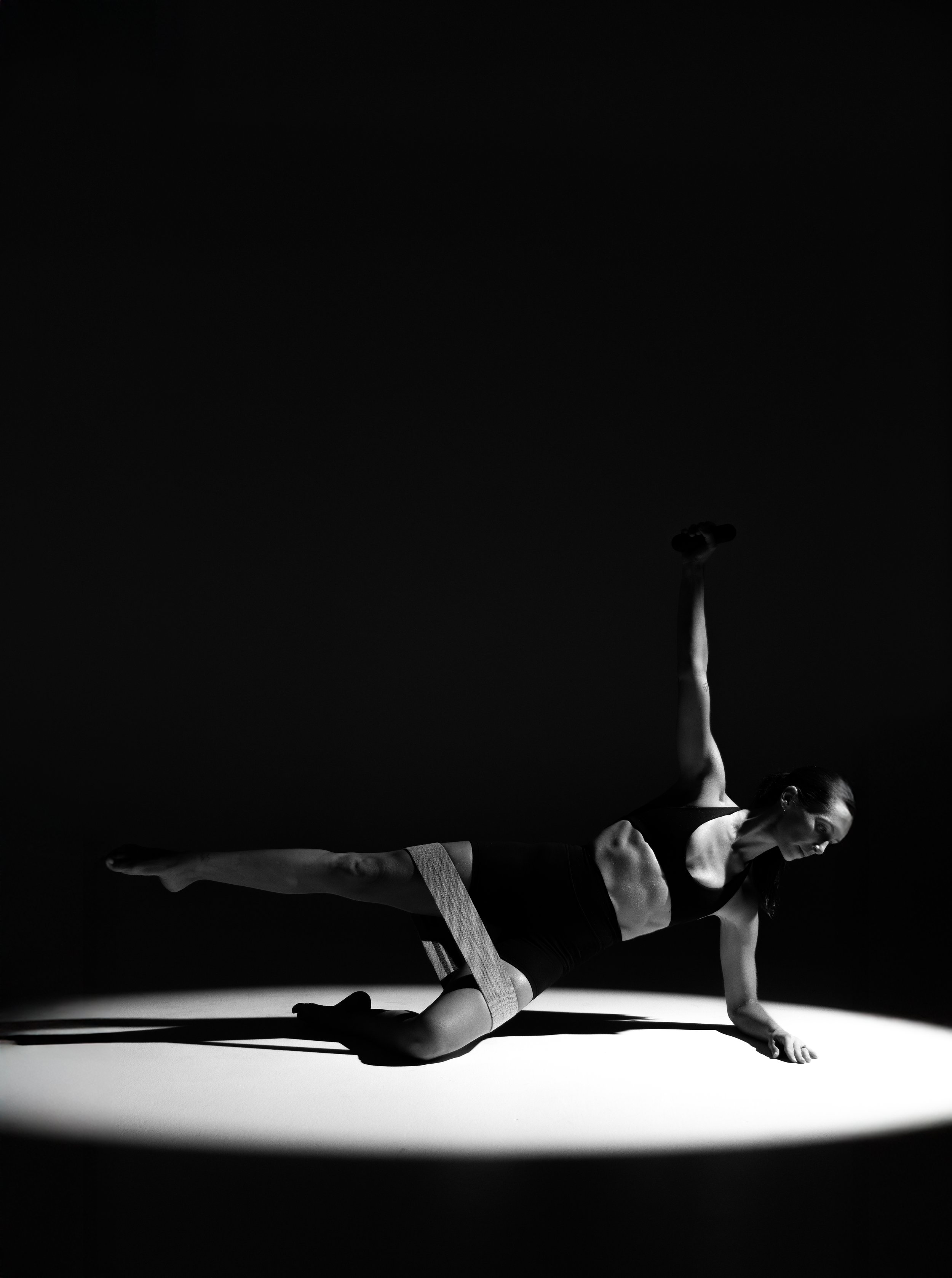 Black and white photo of a female gymnast performing a handstand on a sports mat, wearing athletic attire, with a ladybug on her arm.
