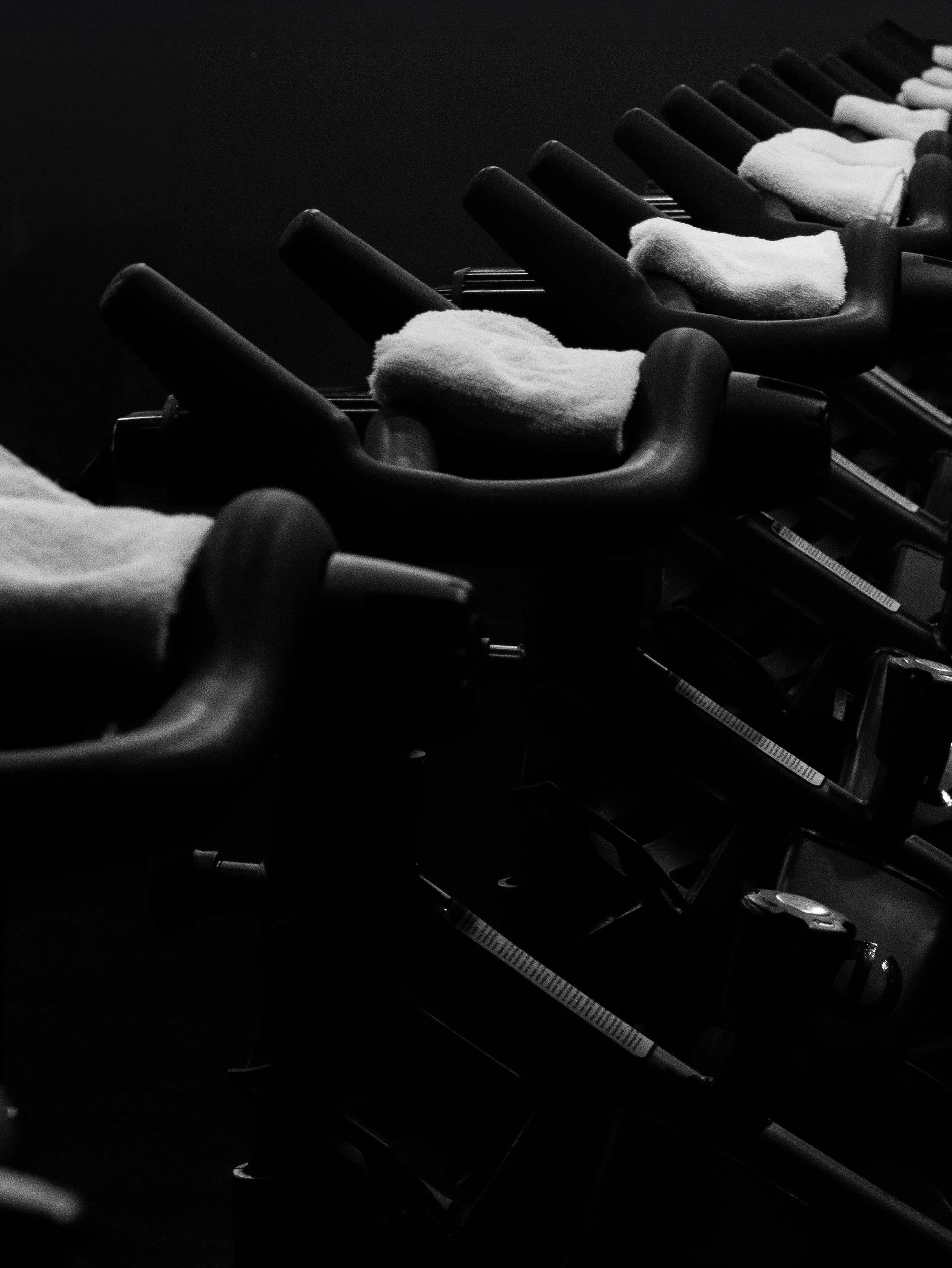 Row of black elliptical objects with white cloth or towel draped over parts of each, arranged in a line against a dark background.