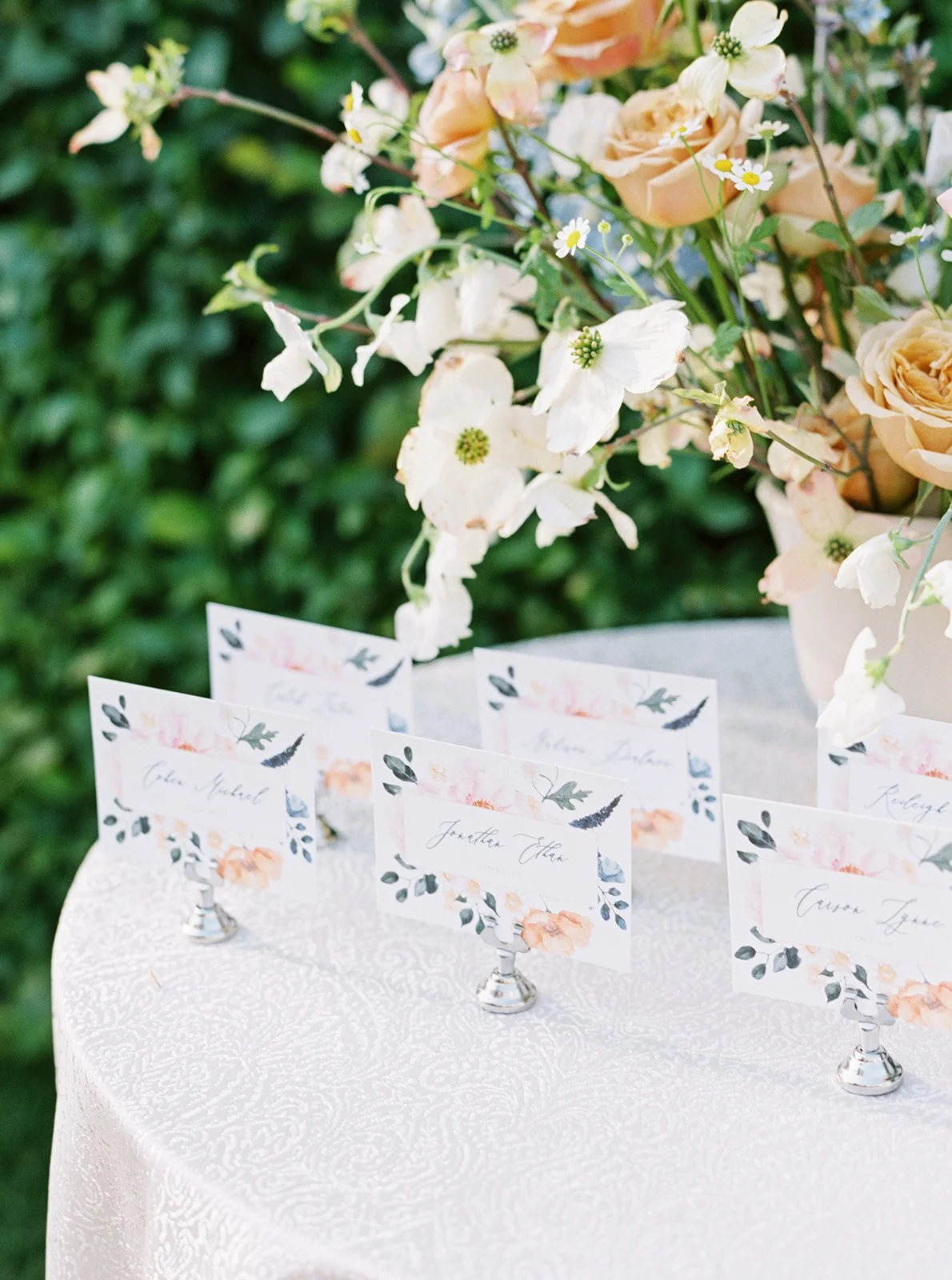 Table with floral arrangement and decorated name cards in holders, California Weddings
