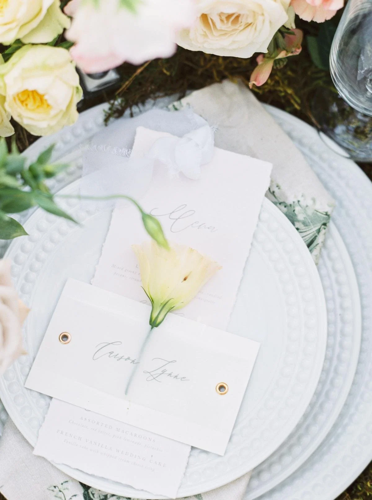 Elegant table setting with menu card, place card, white plate, and white flowers. Orange, California
