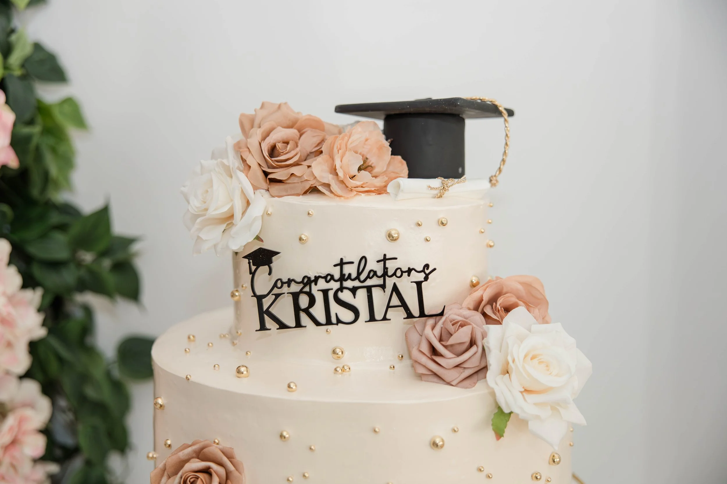 Elegant two-tier graduation cake with floral details and graduation cap topper at a Freeport NY celebration photographed by Moon & Stars Photography.