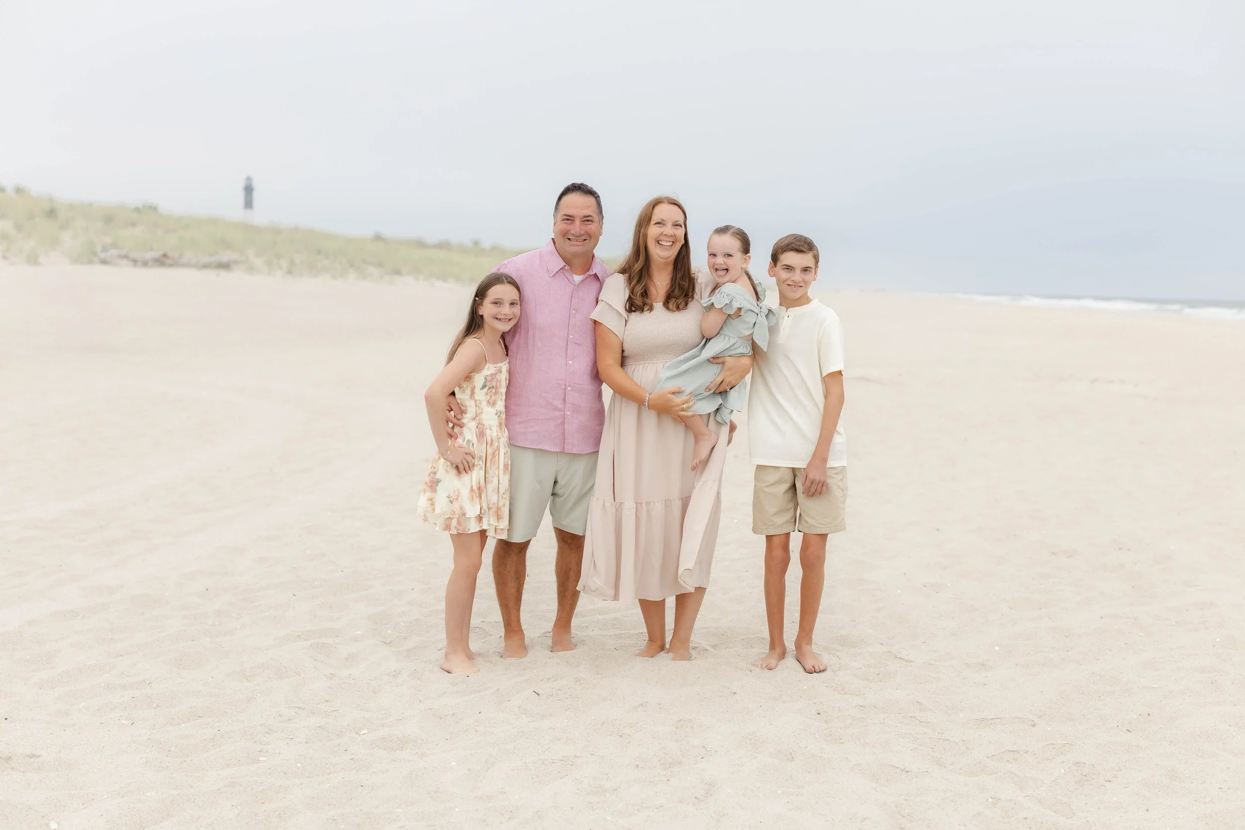 Light and airy family photography session on a Long Island beach with soft neutral tones and dunes in the background, photographed by a Long Island family photographer