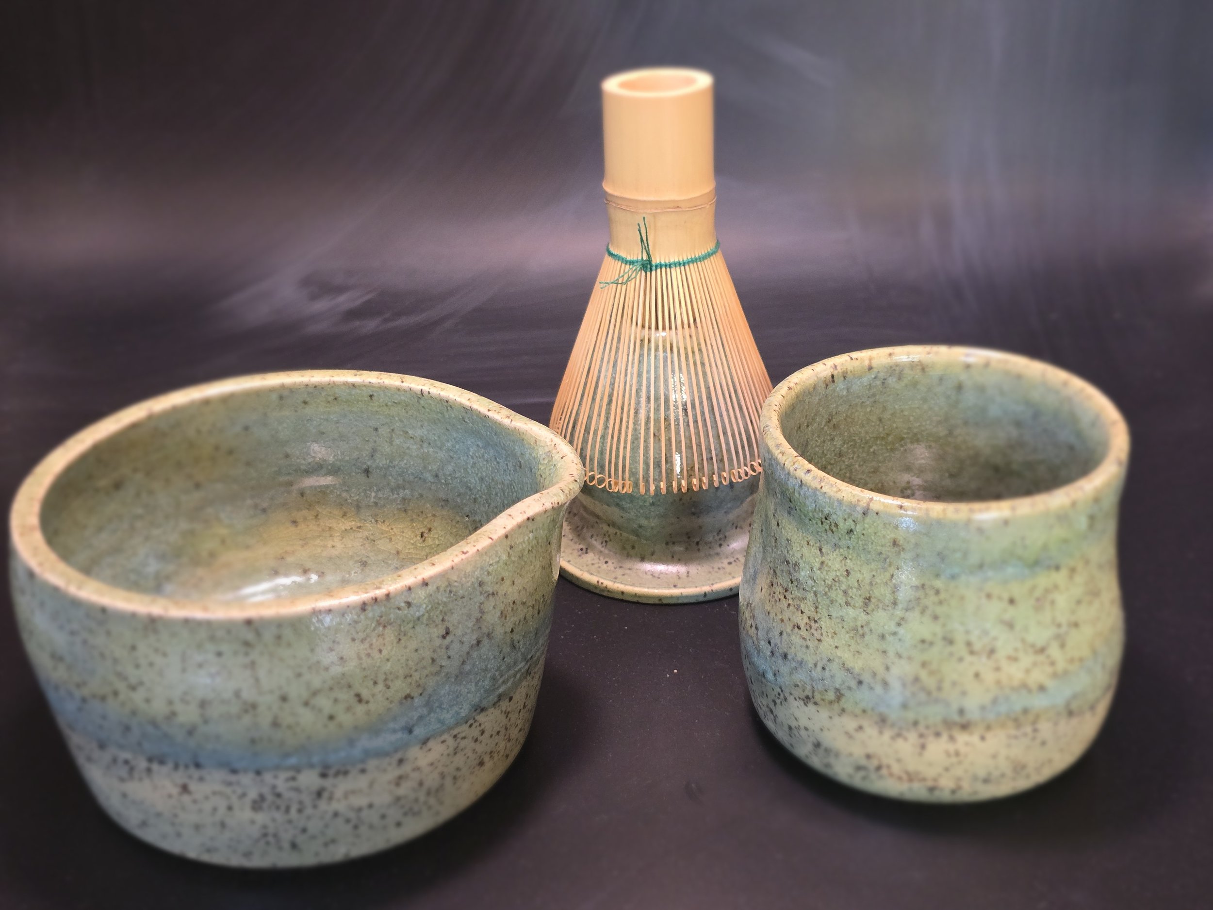 Matcha set with speckled green clay and green glaze on a dark surface.