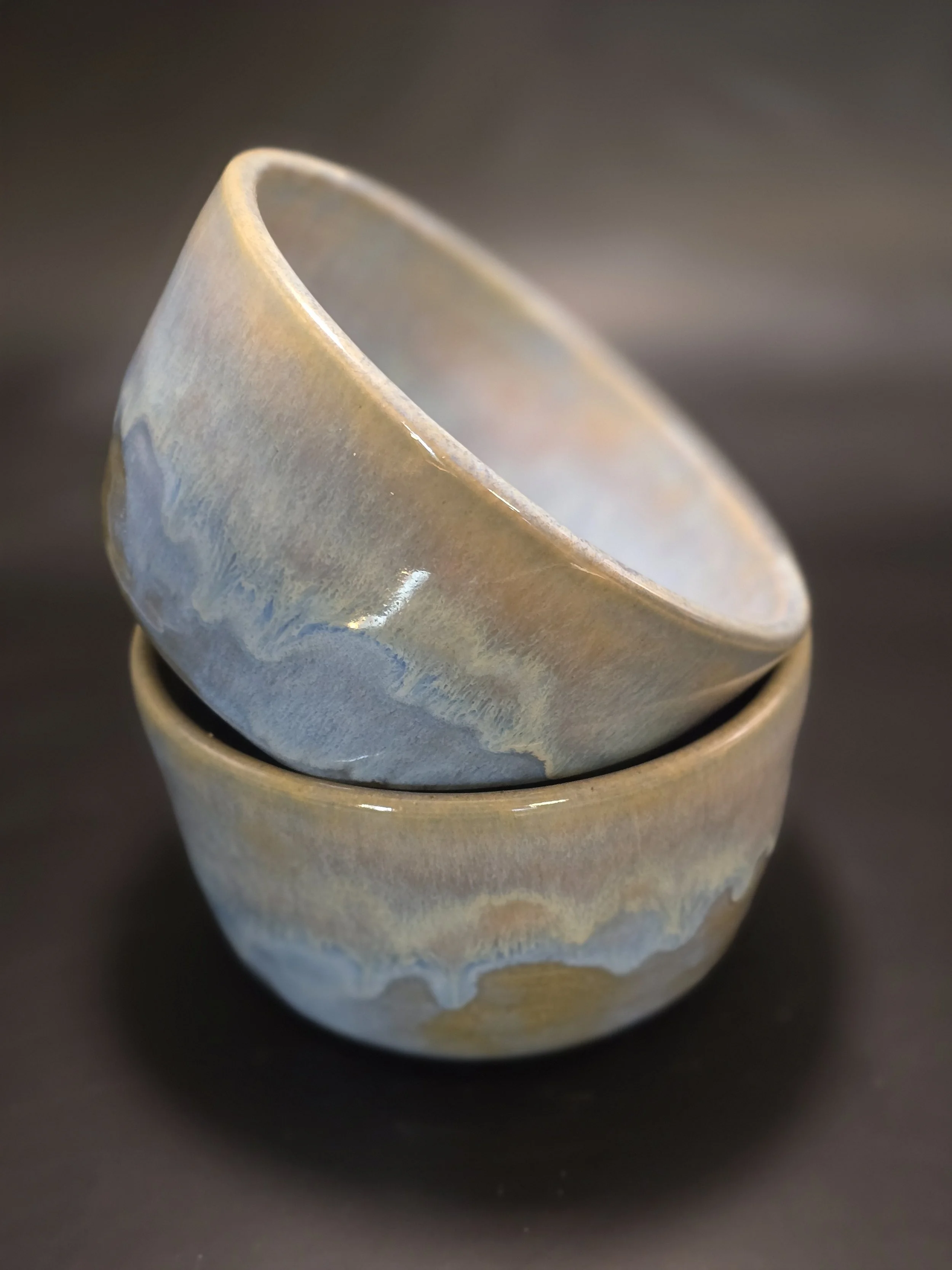 Close-up of a ceramic cup with a textured and glazed surface, sitting on a black surface