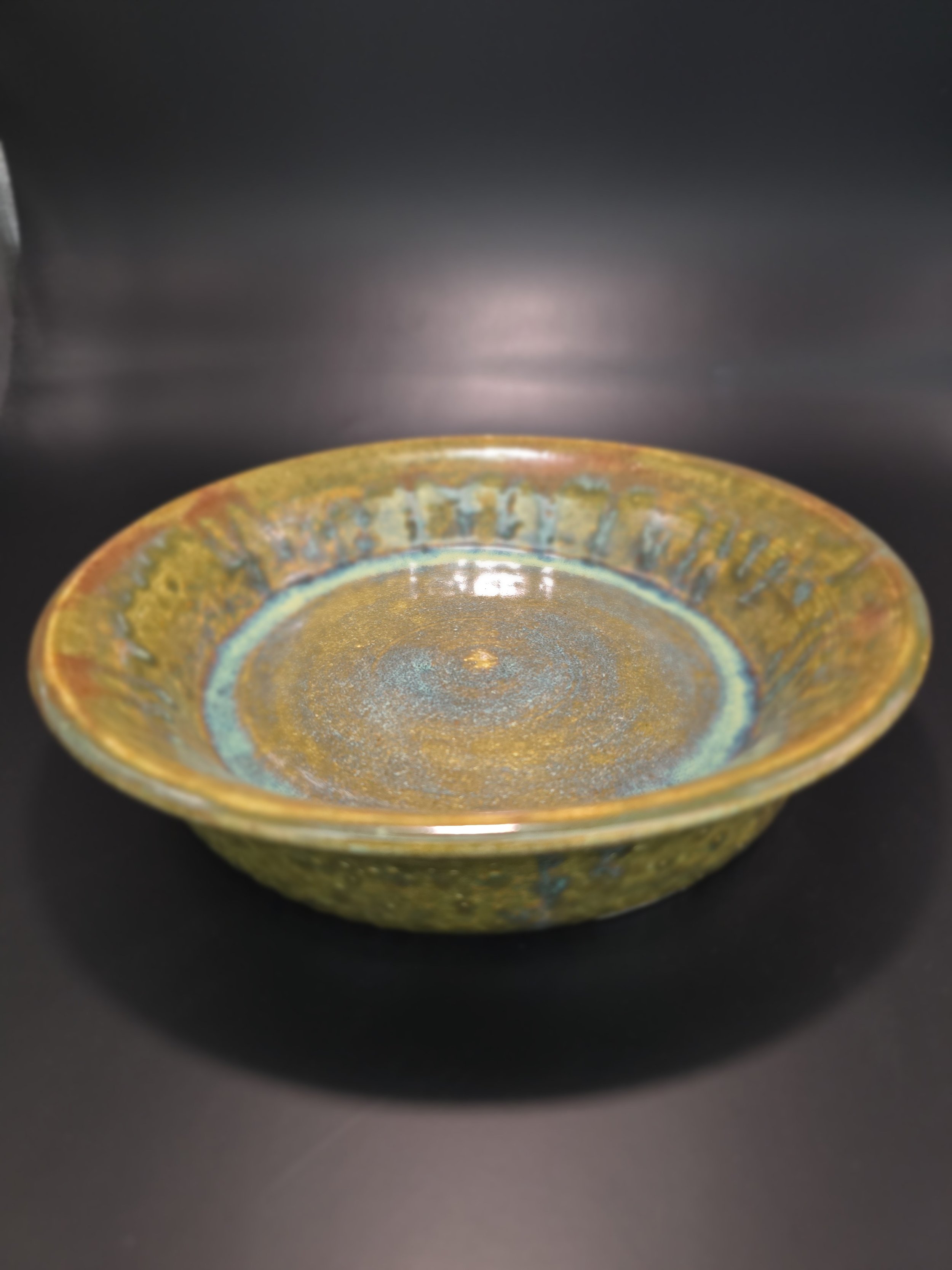 Colorful ceramic bowl with a speckled glaze on a black surface