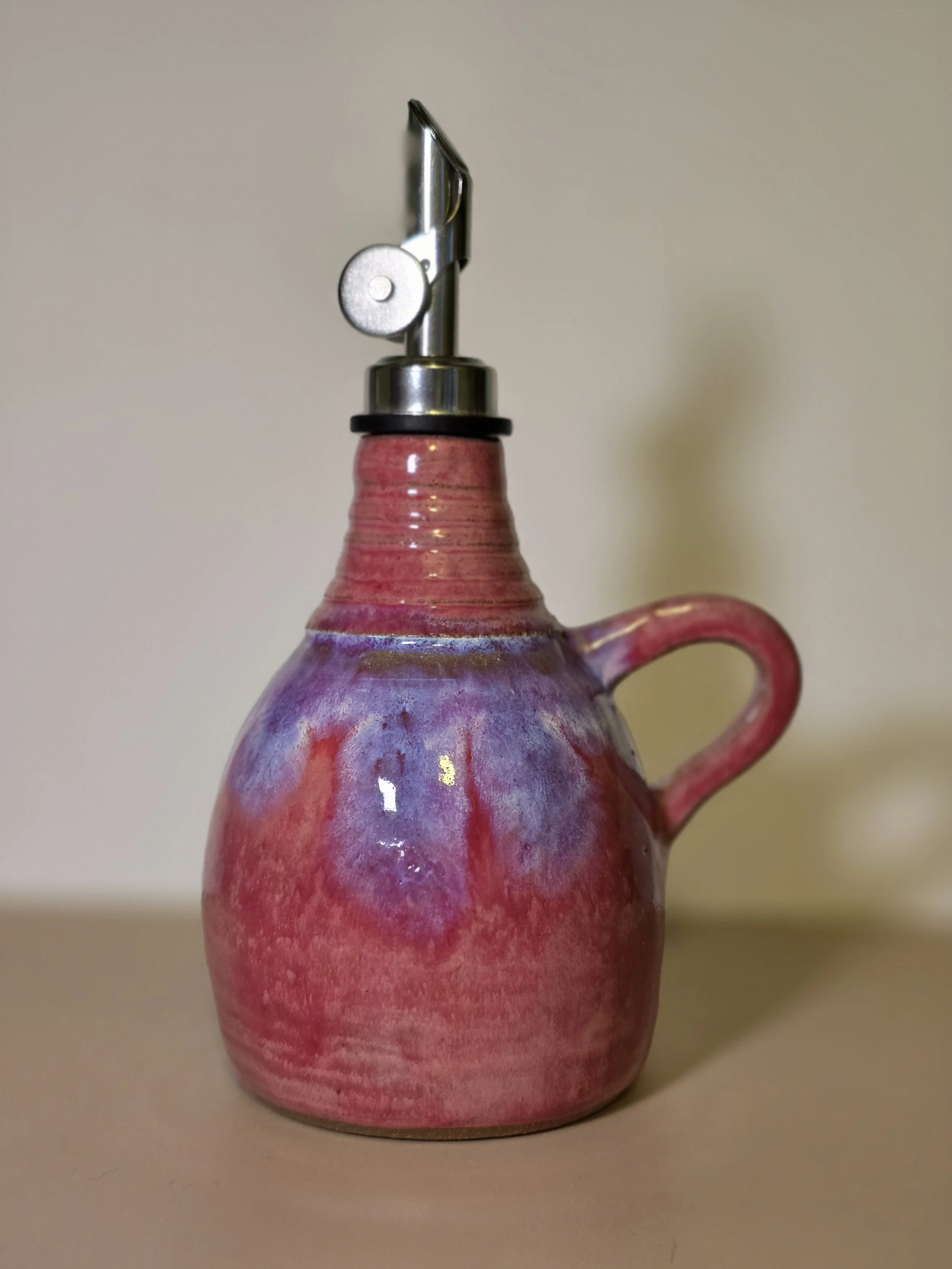 A ceramic mug with a pale pink and purple glaze, used as a stand for a cheese slicer with a wooden handle.